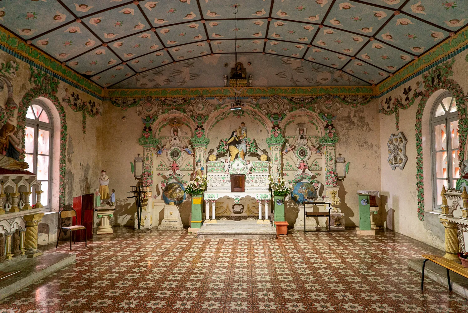 Innenraum einer farbenfroh bemalten Kirche mit Altar und gemaltem Deckengewölbe.