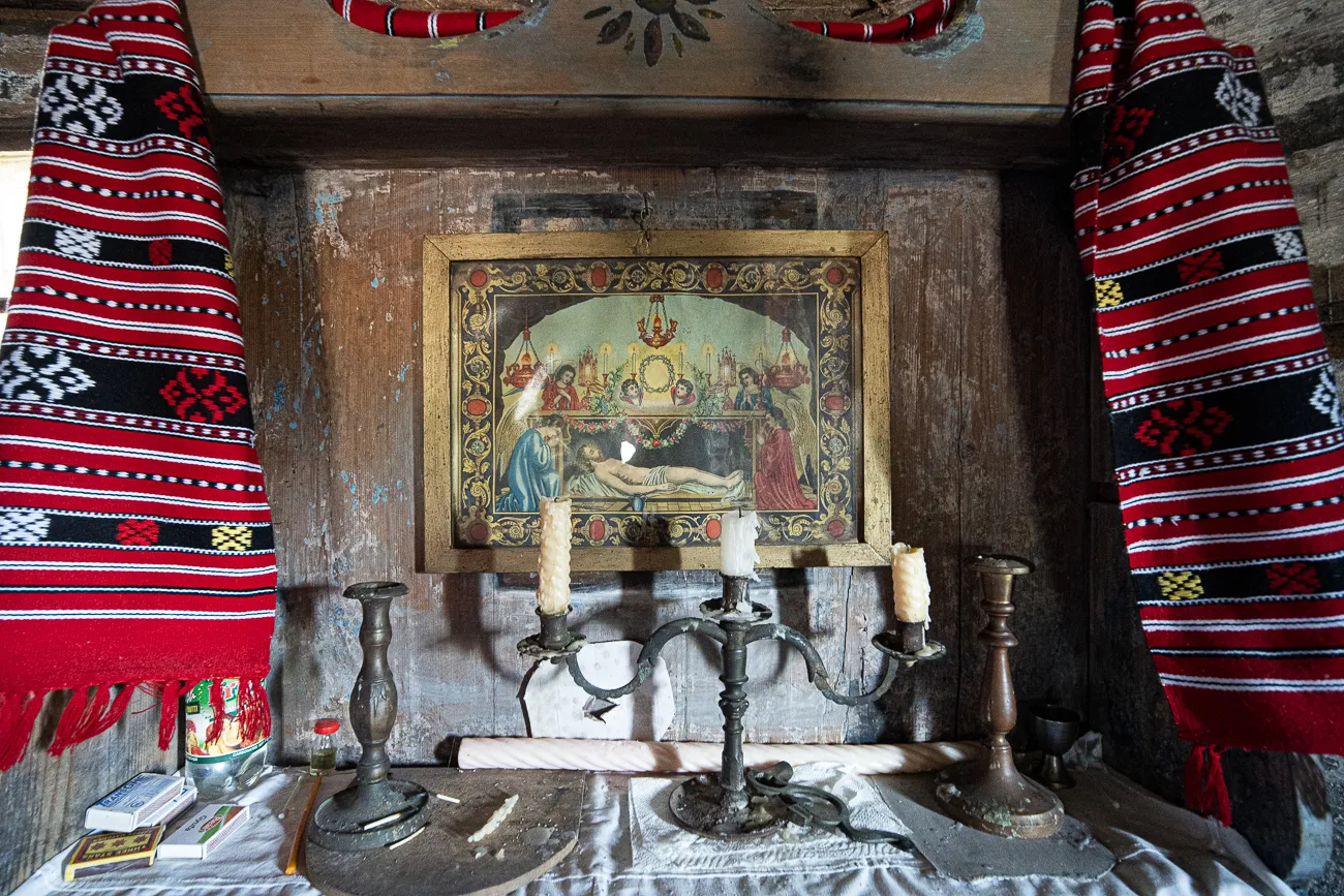 Altar mit religiösem Bild, Kerzen und bunten Stoffen in einer Holzkirche