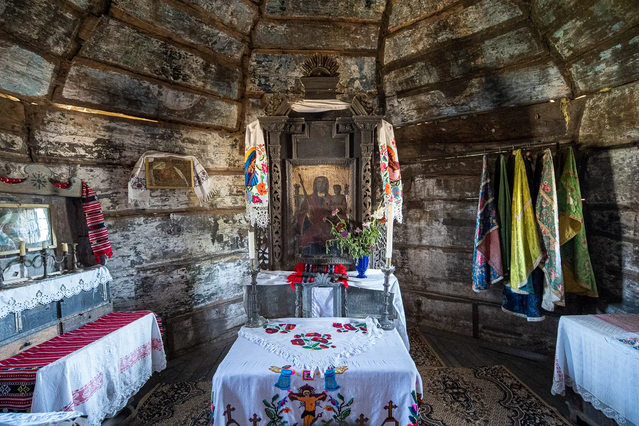 Holzbau mit Altar, Stickereien und farbigen Stoffen an den Wänden