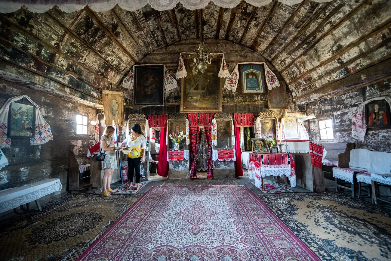 innenraum einer holzkirche mit altartafeln und teppich