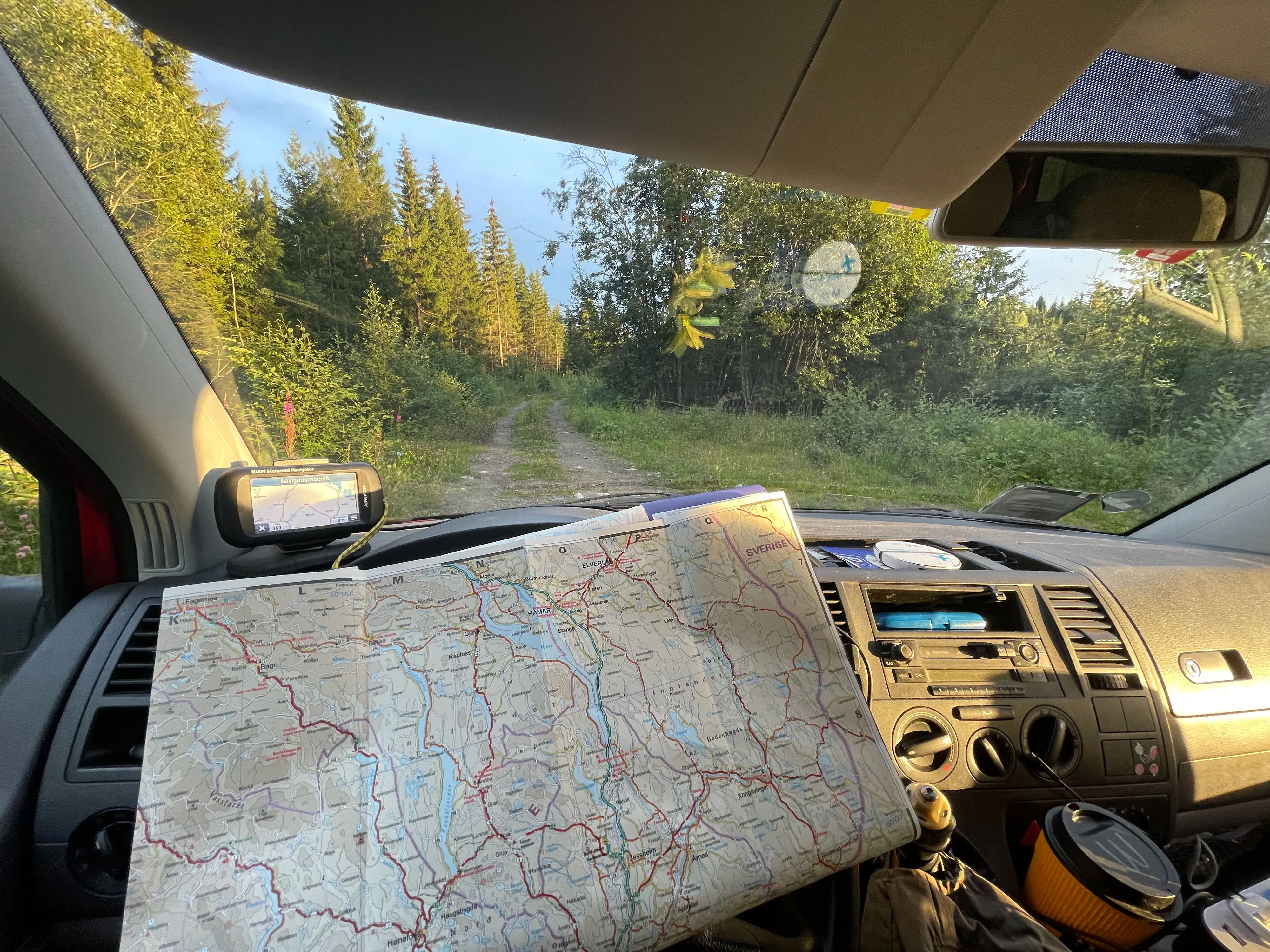 Auto mit Karte im Waldweg, Sonnenlicht durch Bäume