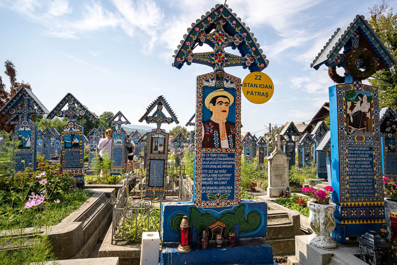 Farbenfrohe, bemalte Grabkreuze in einem Friedhof unter blauem Himmel.