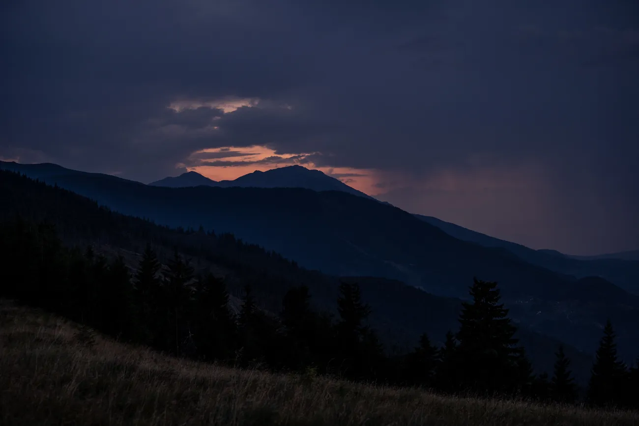Dämmerung über bewaldeten Bergen mit orangefarbenem Himmel