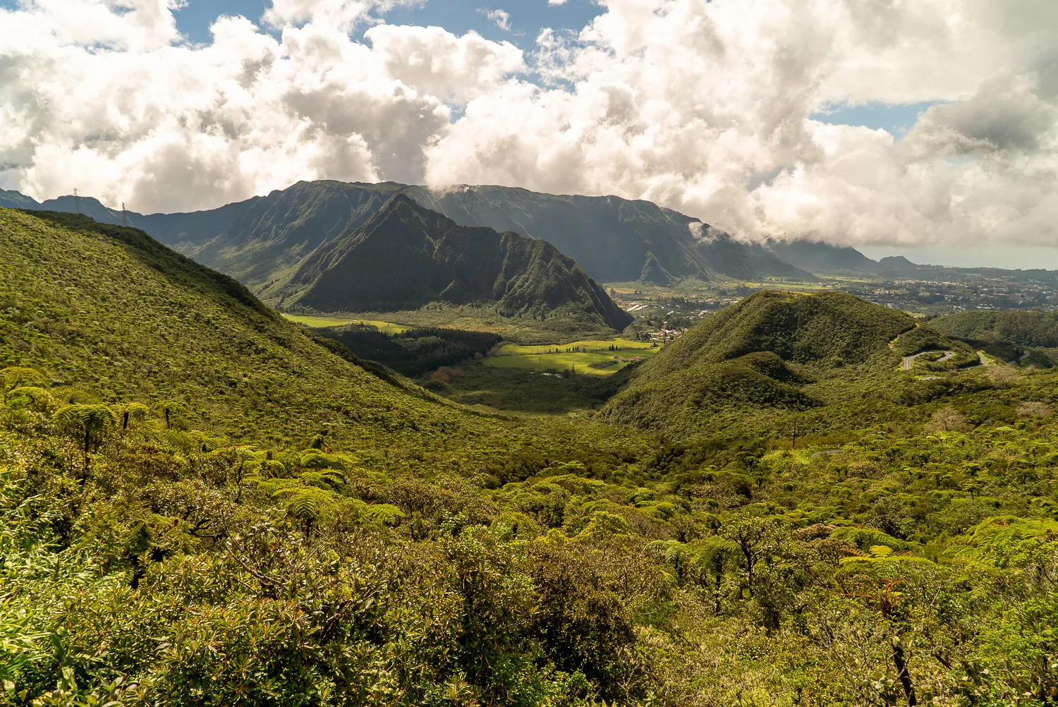 Grüne Hügel und Berge unter bewölktem Himmel mit Tal im Vordergrund