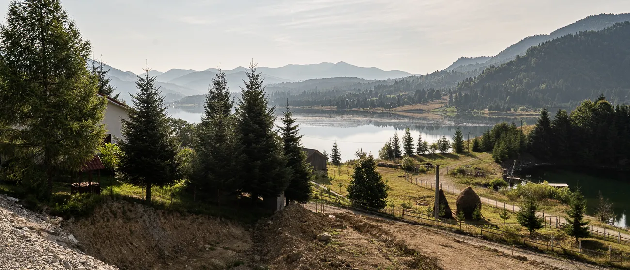 Bergsee mit Wald und Häusern im Hintergrund