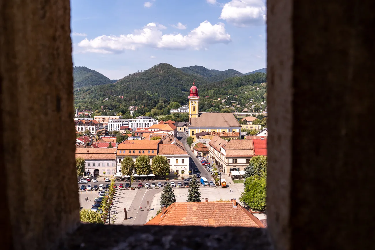 Stadtansicht durch Steinfenster mit Kirche und Bergen im Hintergrund