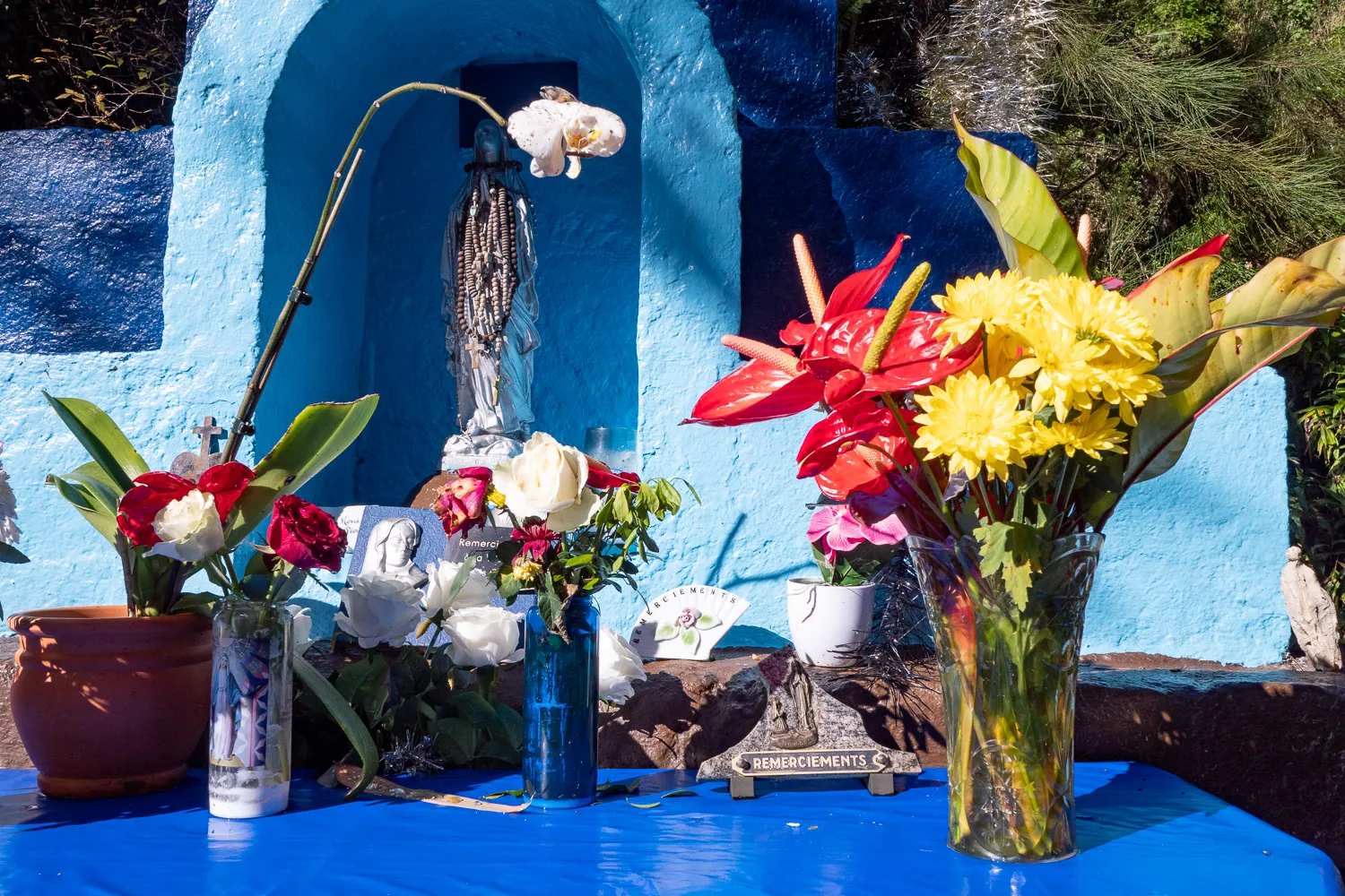 Blumenarrangements vor blauer Wand mit Statue und Dankesinschrift