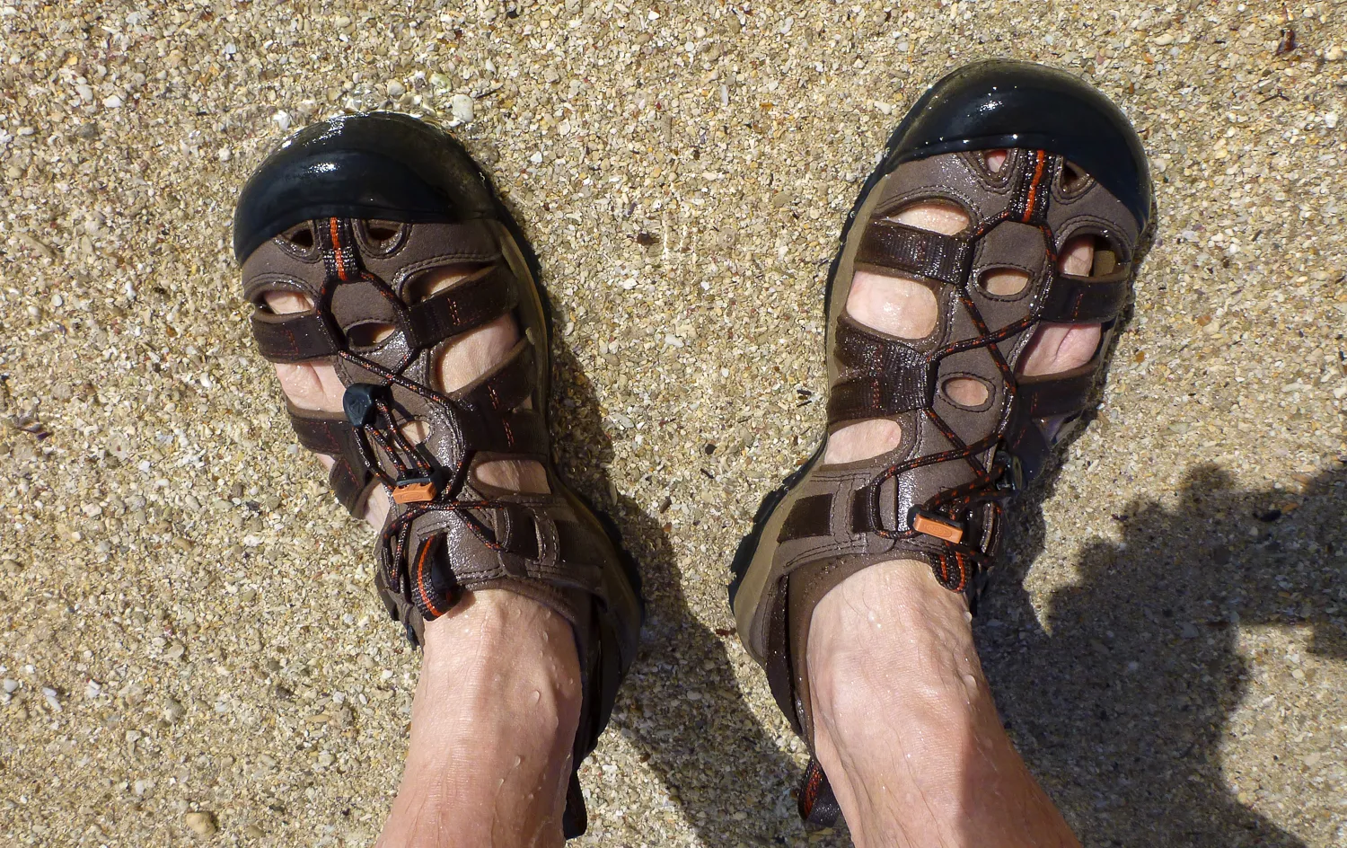 braune sandalen auf kiesstrand