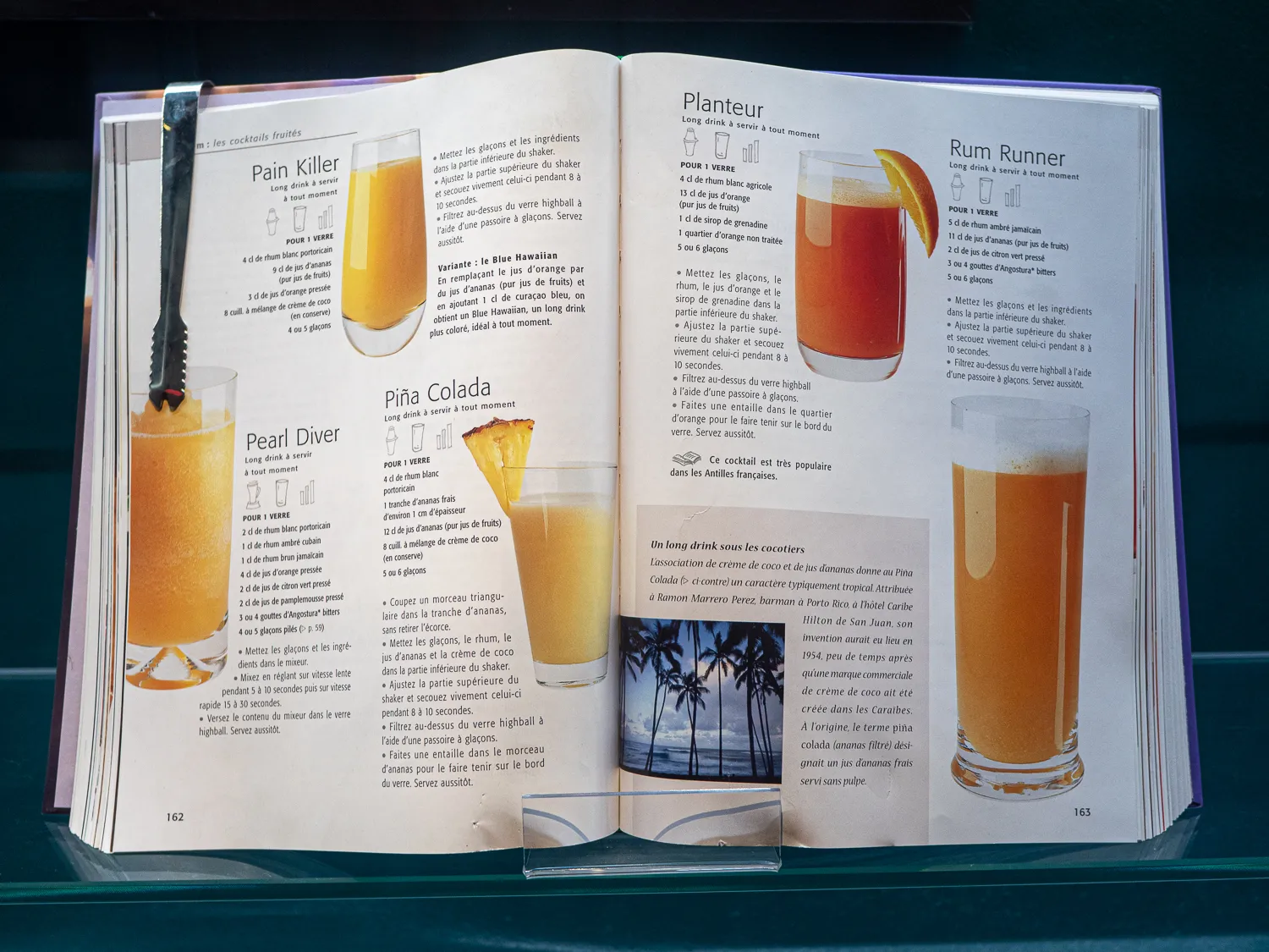 Offene Buchseite mit Cocktailrezepten und Fotos von Getränken