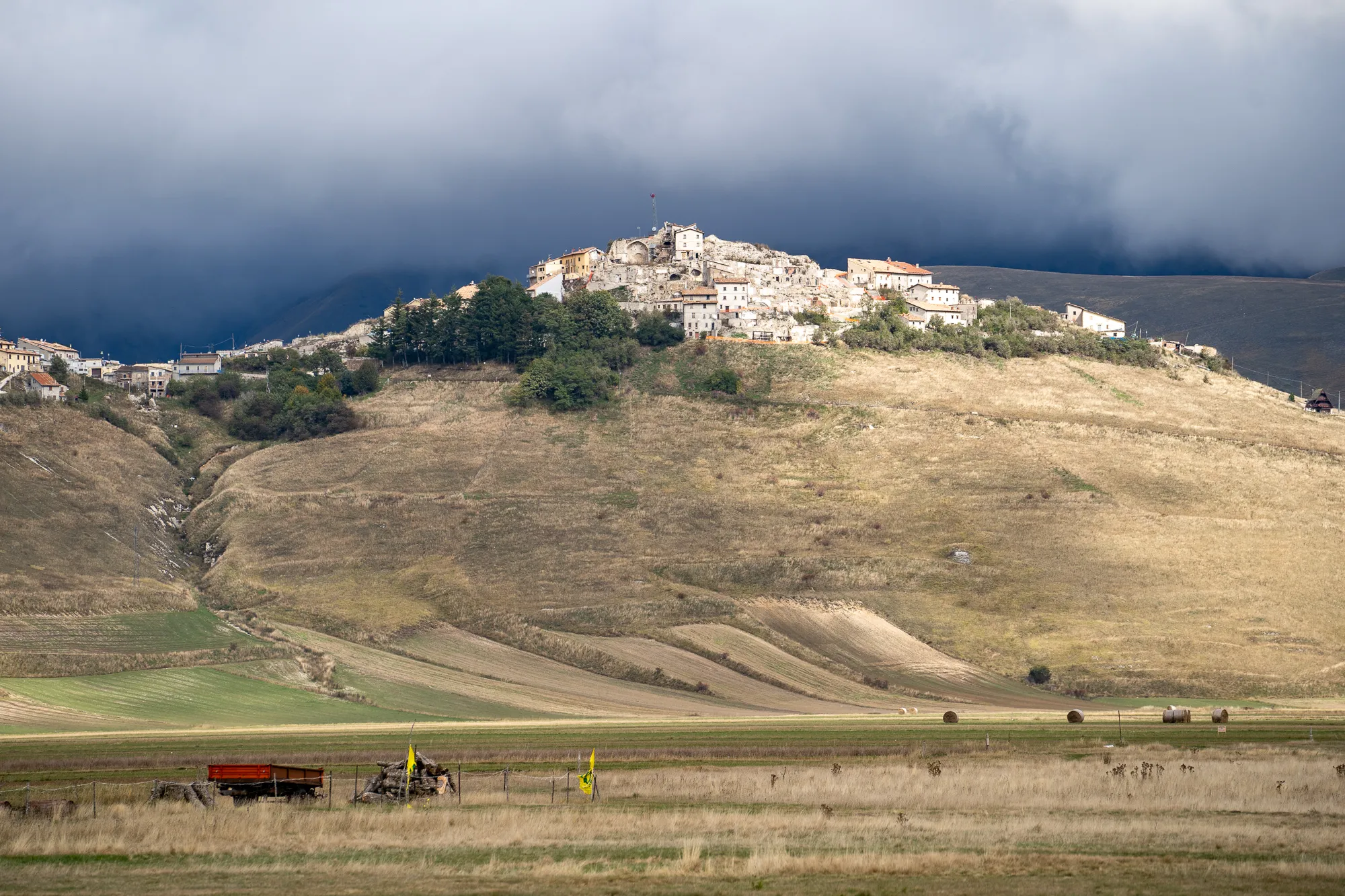 Dorf auf steiler Hanglandschaft unter dunklen Wolken