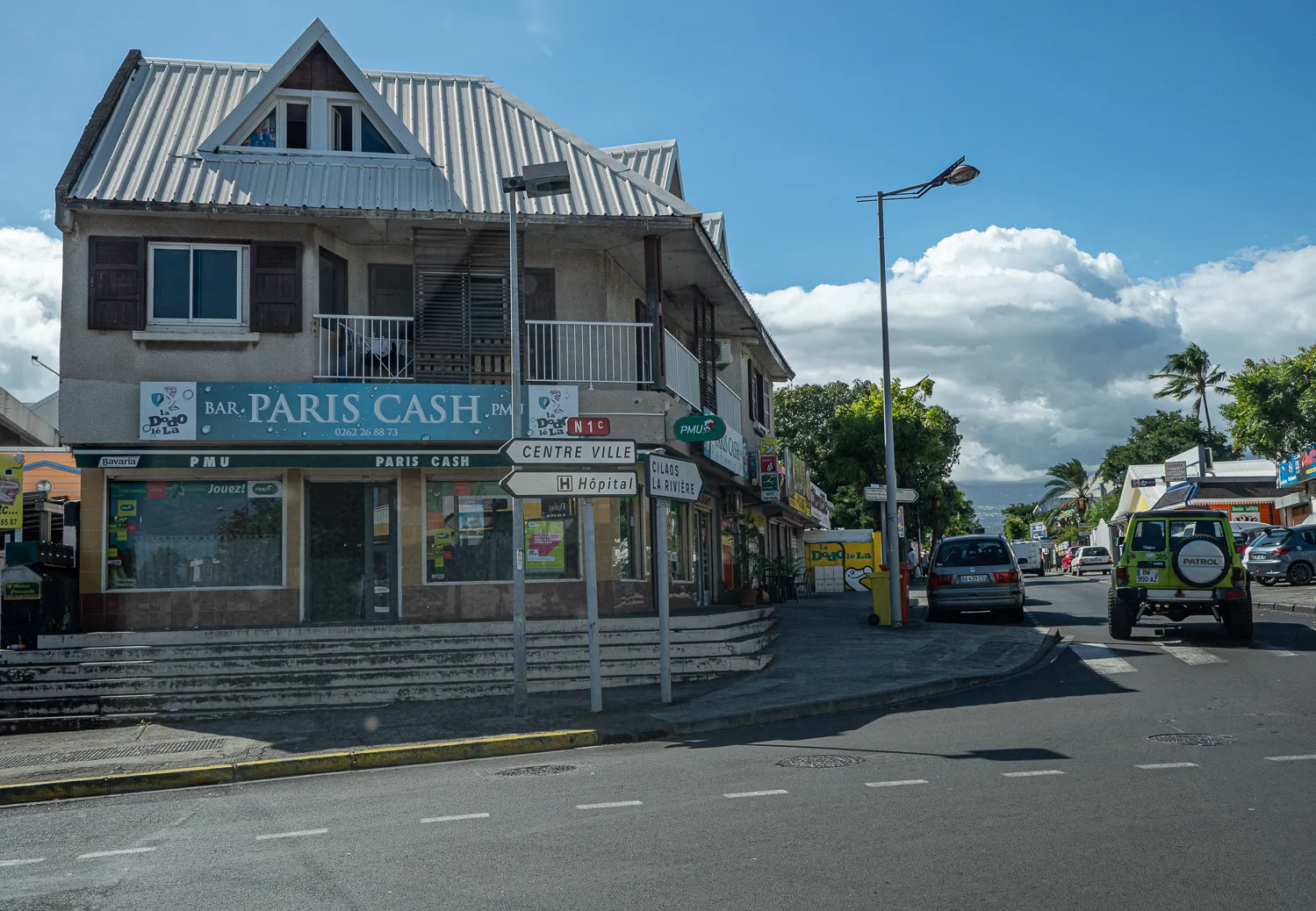 Straßenszene in Cilaos mit Geschäften und Verkehr unter blauem Himmel