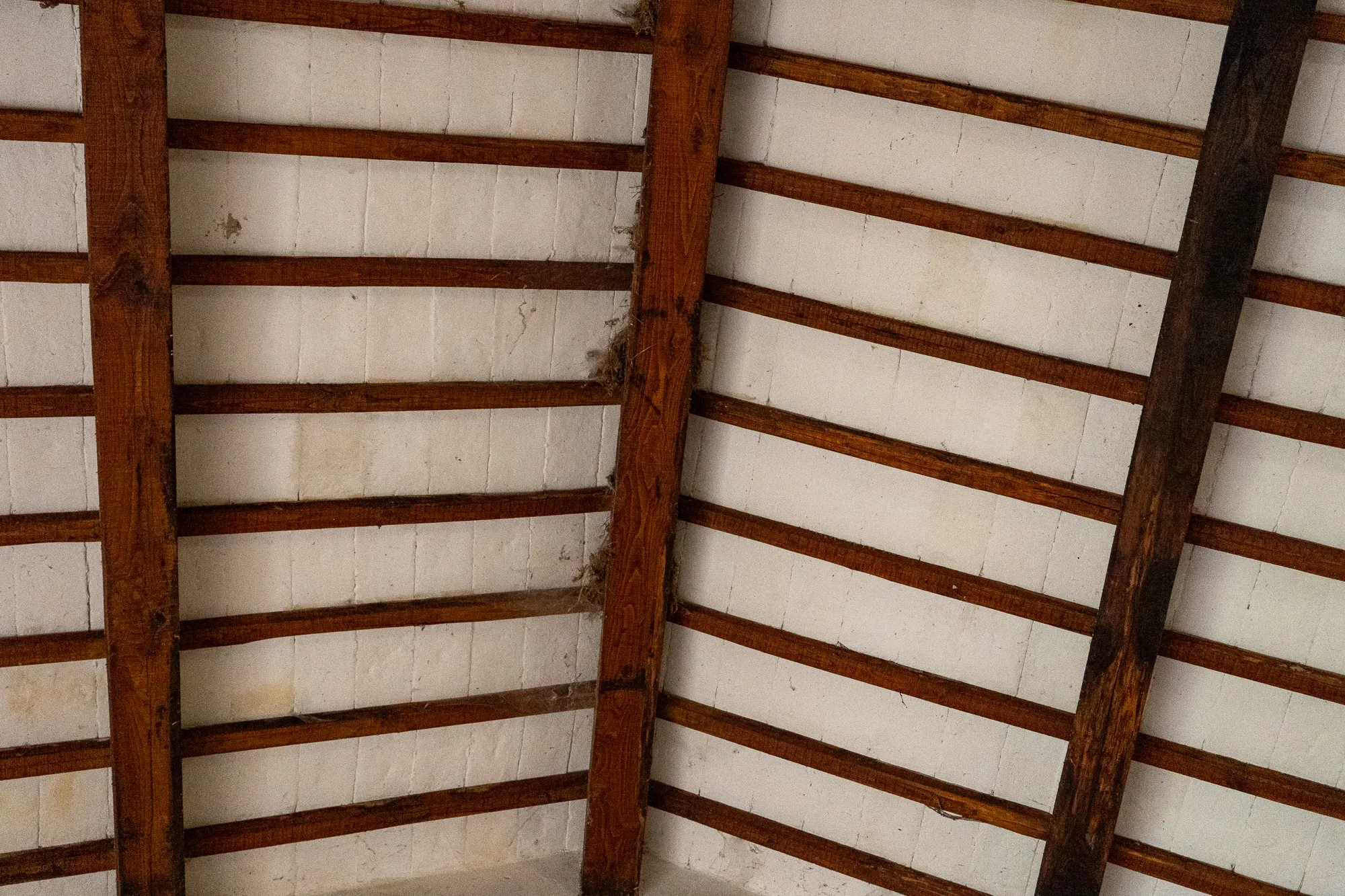 Holzbalken und weiße Wände im Dachstuhl eines alten Gebäudes