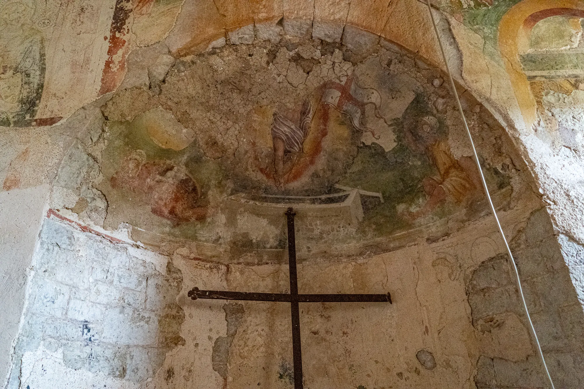 Alter Wand- und Deckenmalerei in einer Kirche mit Kreuz im Vordergrund