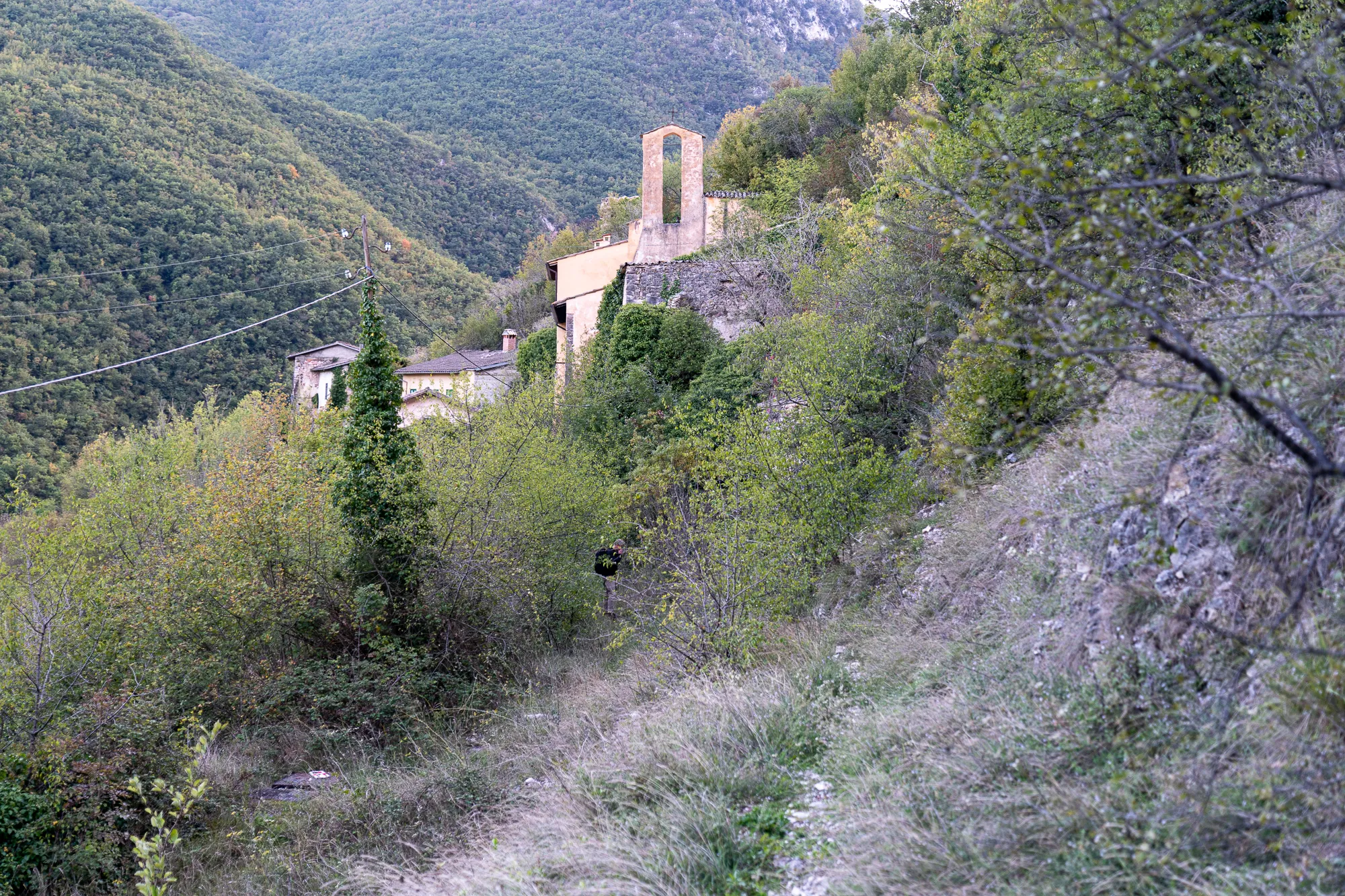 kleines dorf auf steiler haldenhang mit steinernen kirche und dichten bewaldeten hängen