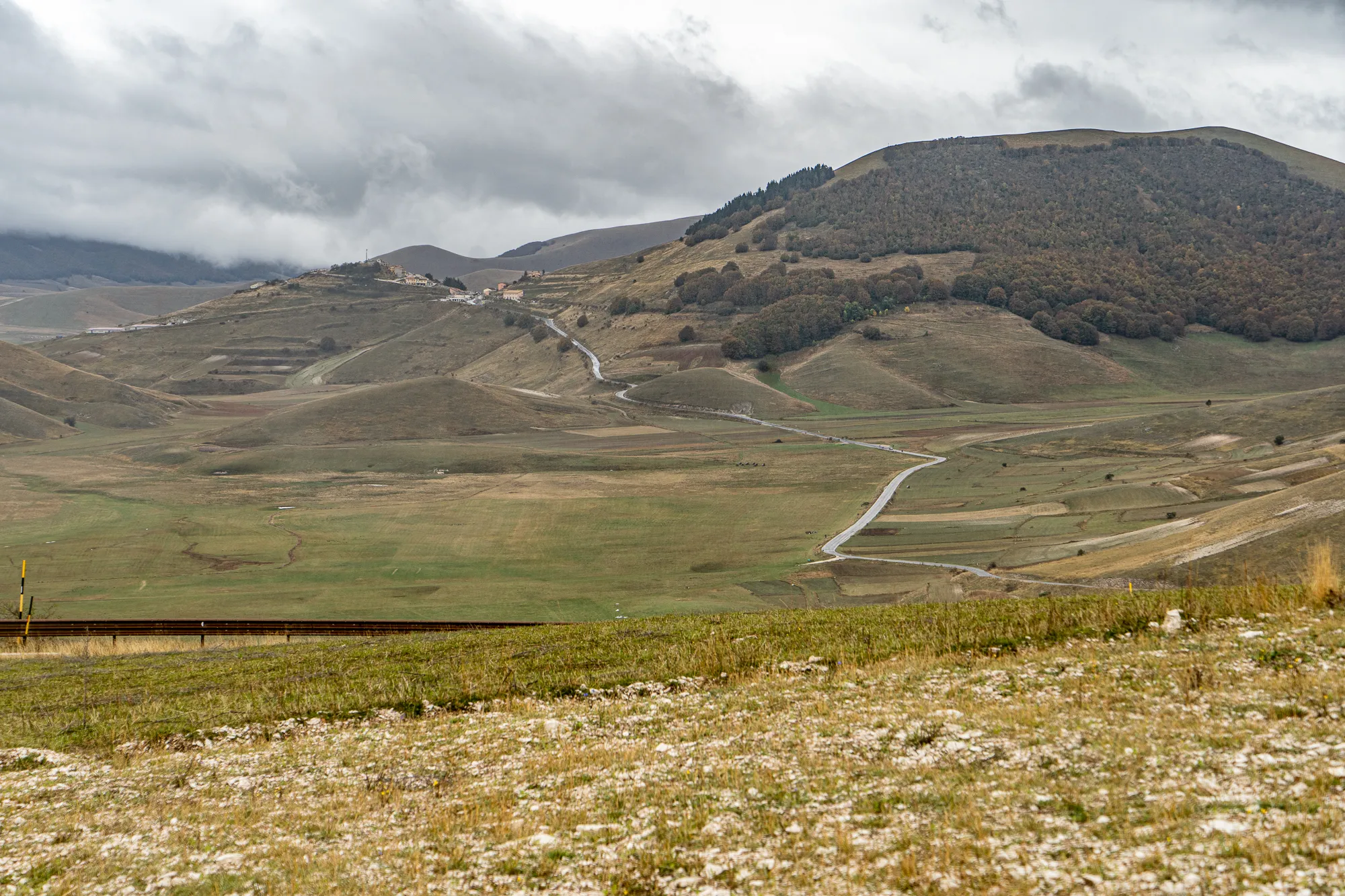 Berglandschaft mit Wegen und Feldern unter bewölktem Himmel