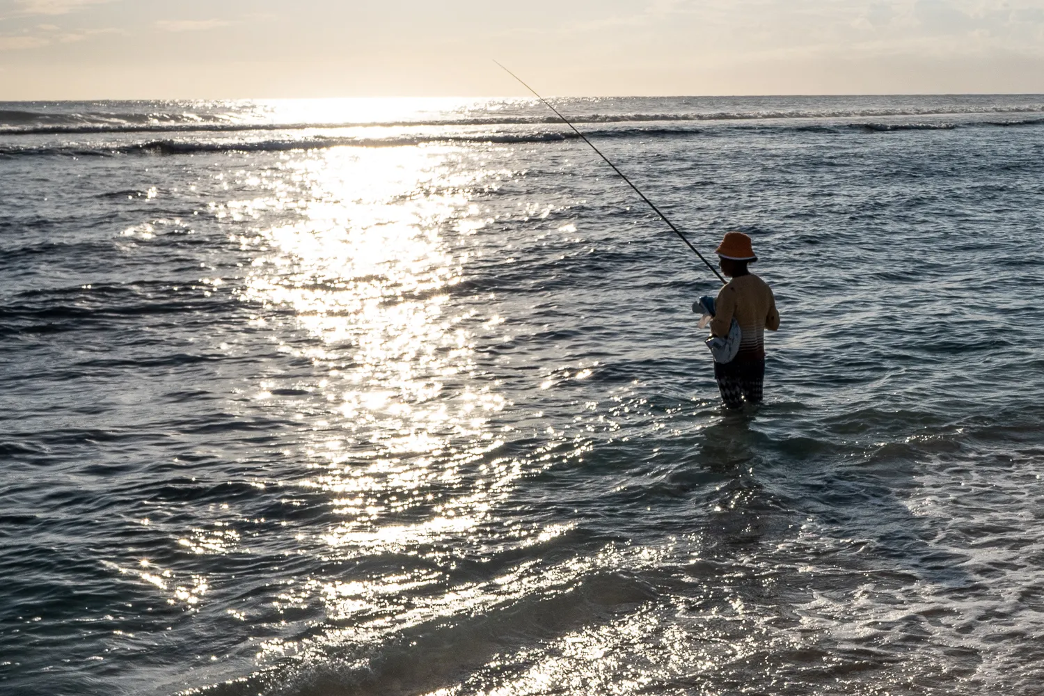 Mensch fischt im Sonnenlicht am Strand