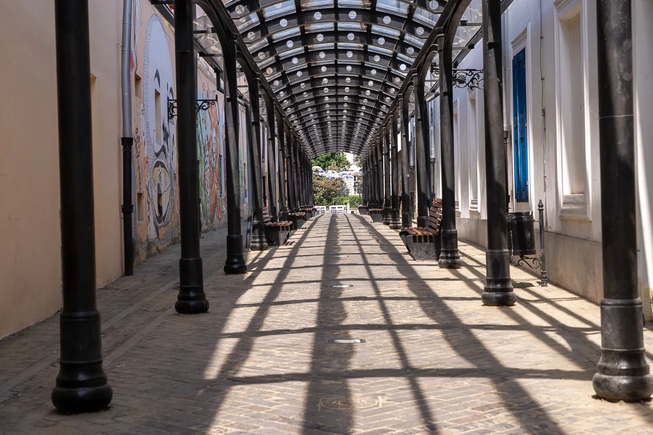 Lange Gasse mit schattigen Bögen und bunten Wandmalereien