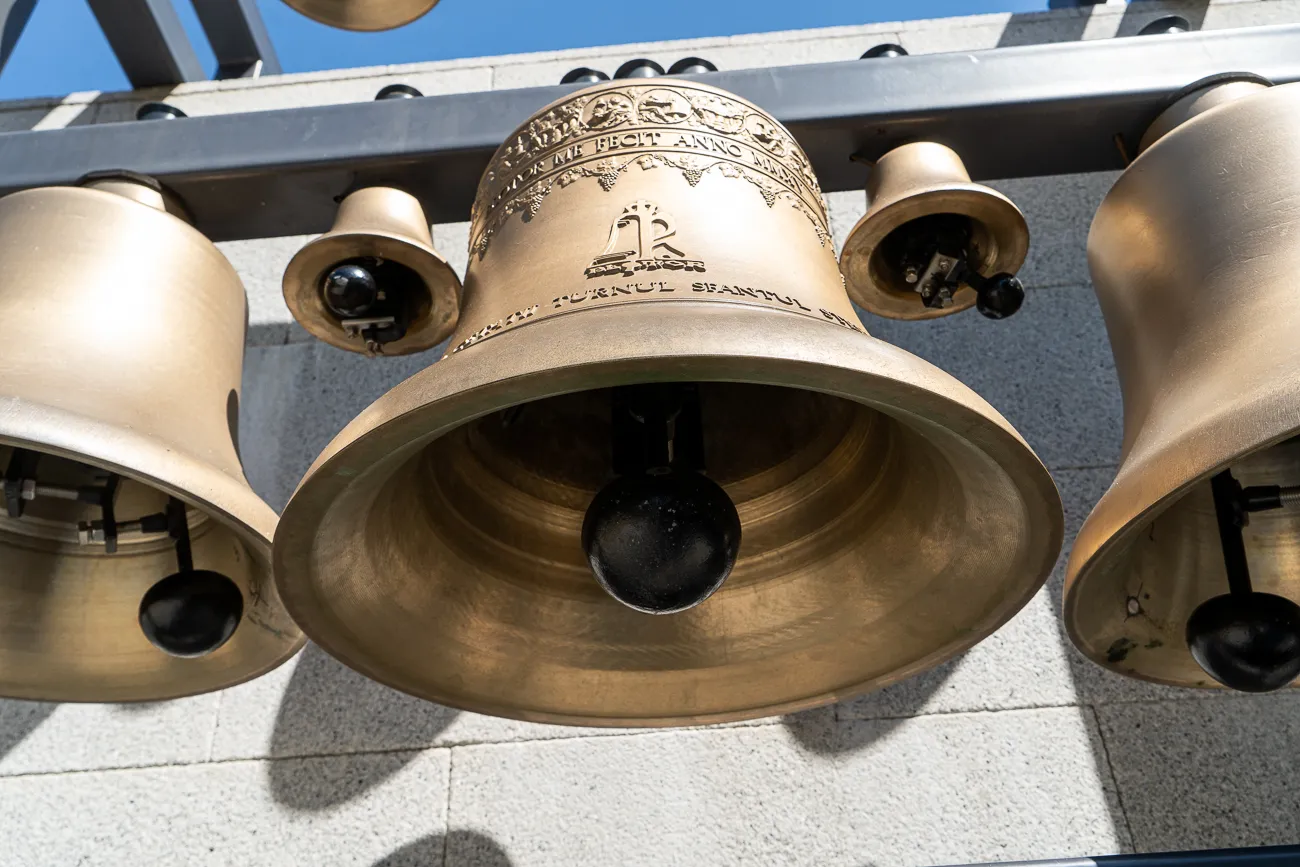 Gusseisen-Glocken an einer Wand, Sonnenlicht reflektiert auf Metall.
