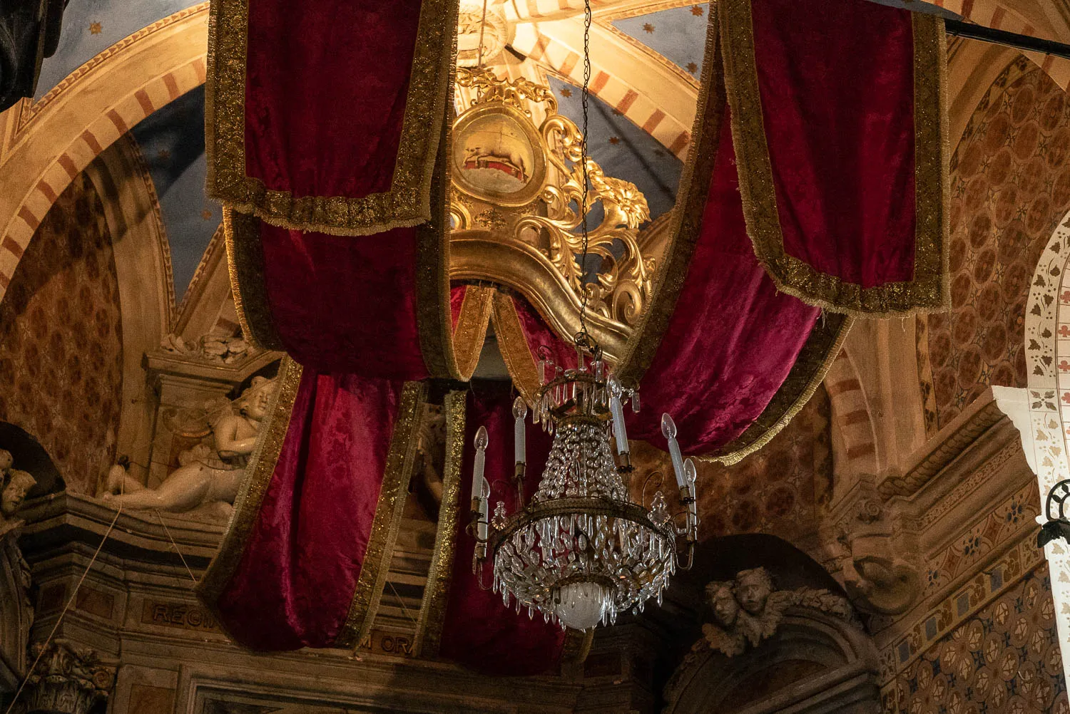 Goldener Kronleuchter mit roten Samtvorhängen in einer Kirche