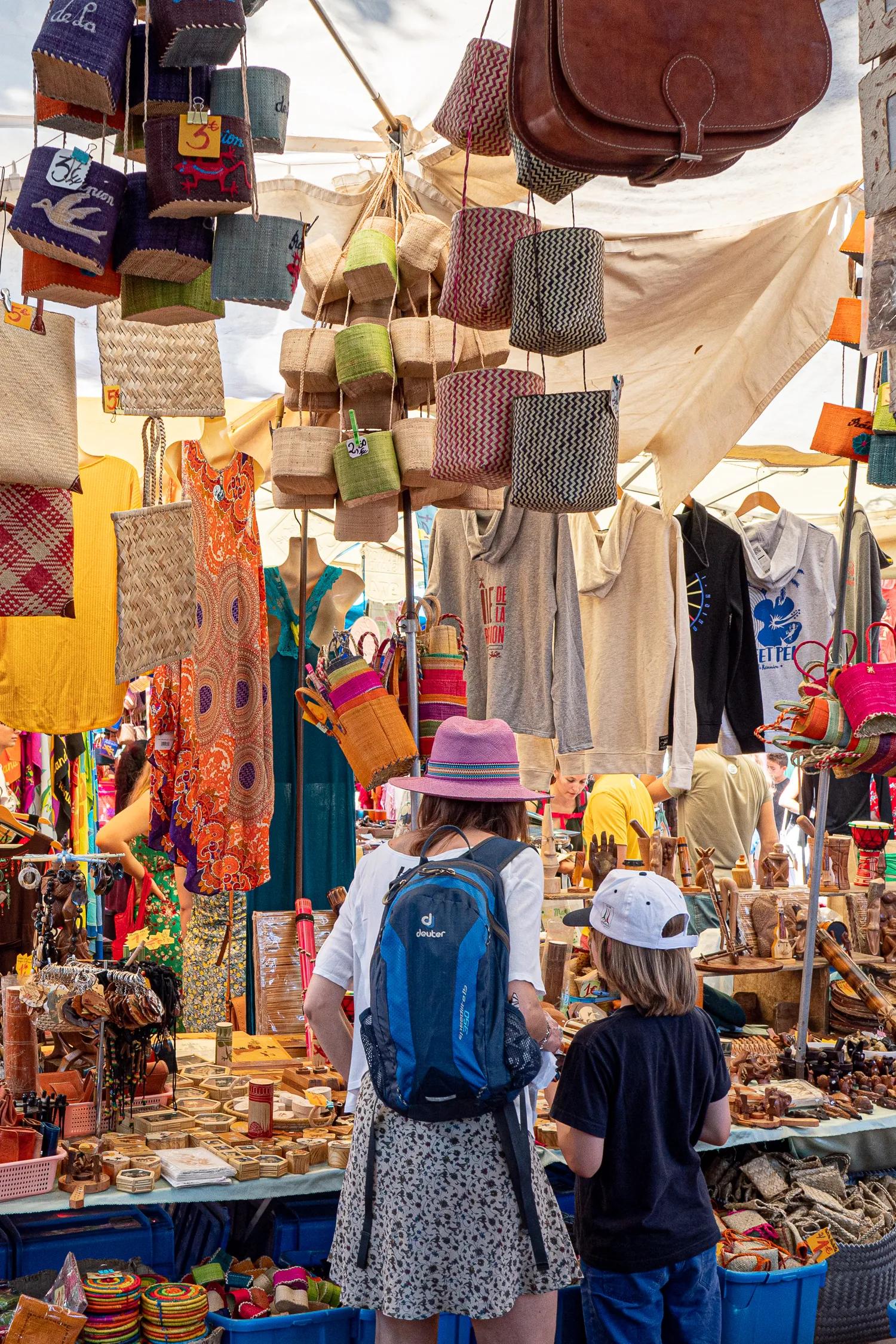 Marktstände mit bunten Handarbeiten und Besucherinnen im Hintergrund