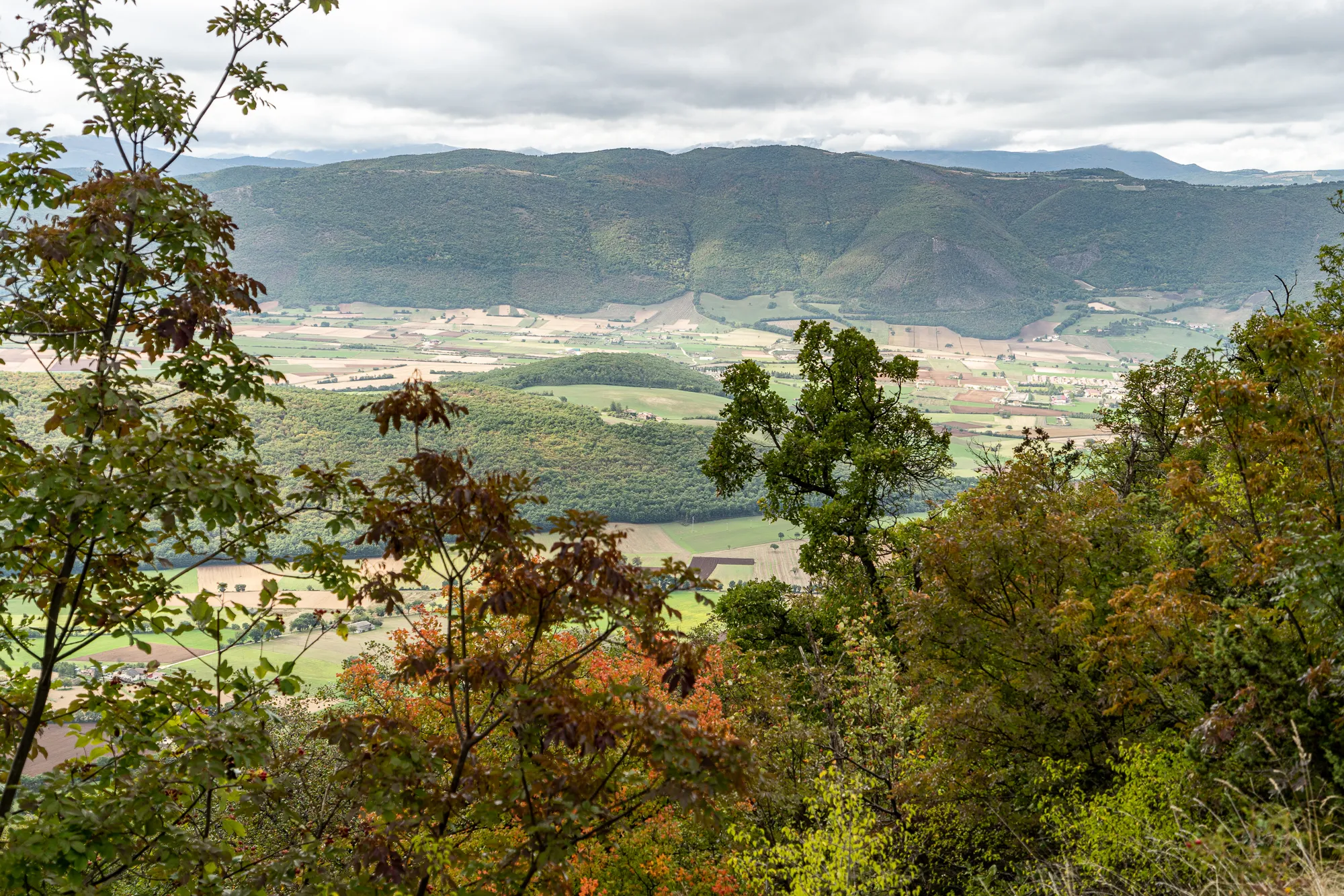 Blick auf Tal mit Feldern und Bergen im Herbst