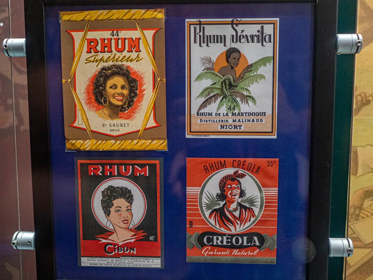 Vier historische Rum-Verpackungen in einem Glasvitrinenrahmen