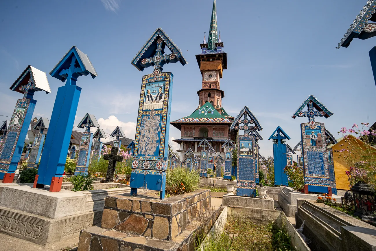 Farbige Holzgrabsteine und Kirche im Freien unter blauem Himmel