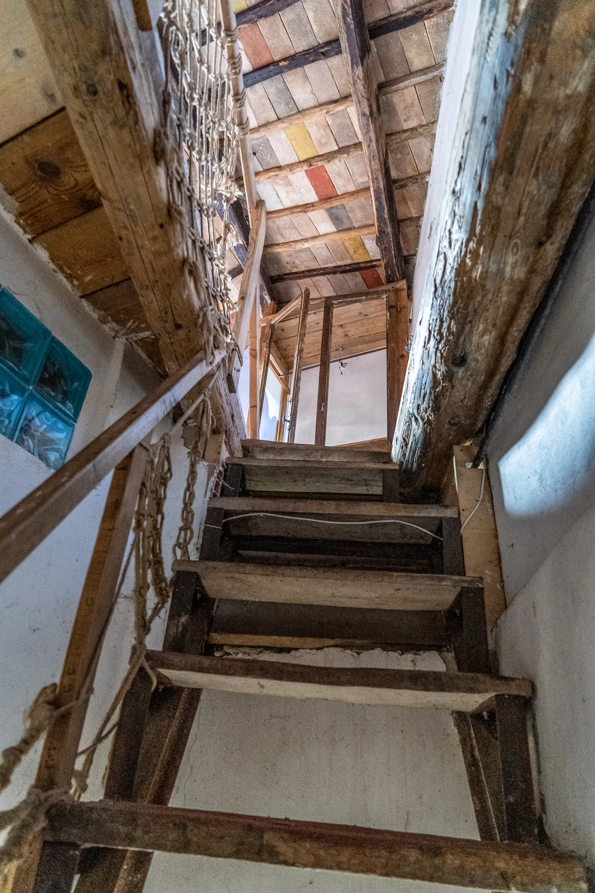 Holztreppe mit Kettenbrüstung und farbigem Holzdach im Inneren
