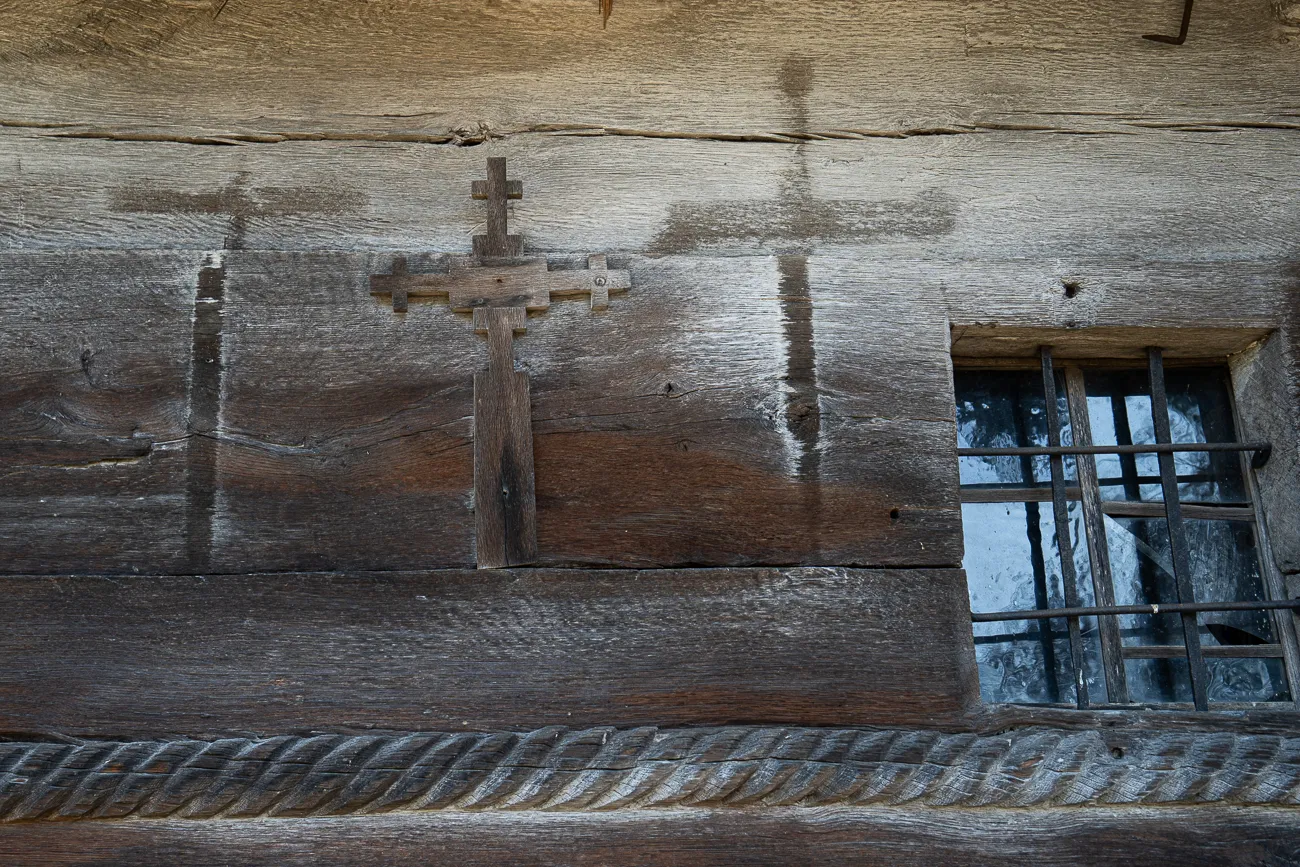Holzverkleidung mit Kreuz und Fenster mit Gitter
