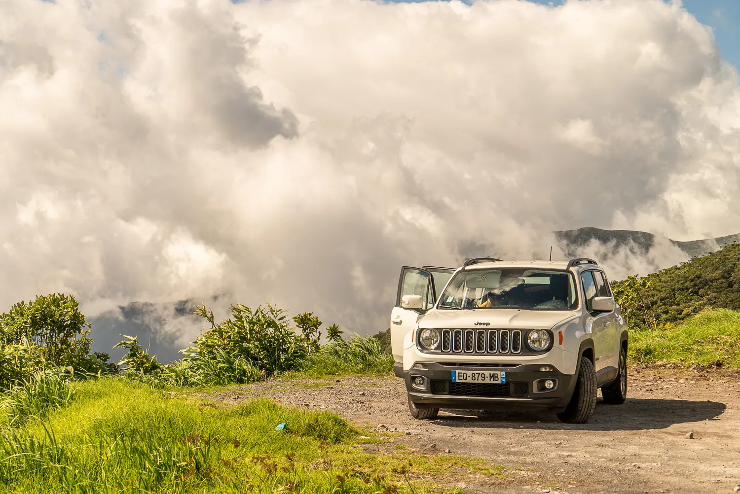 weißer jeep auf schotterweg unter bewölktem himmel