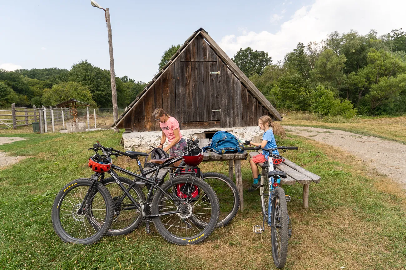 Zwei Kinder mit Mountainbikes vor einem alten Holzschuppen im Grünen