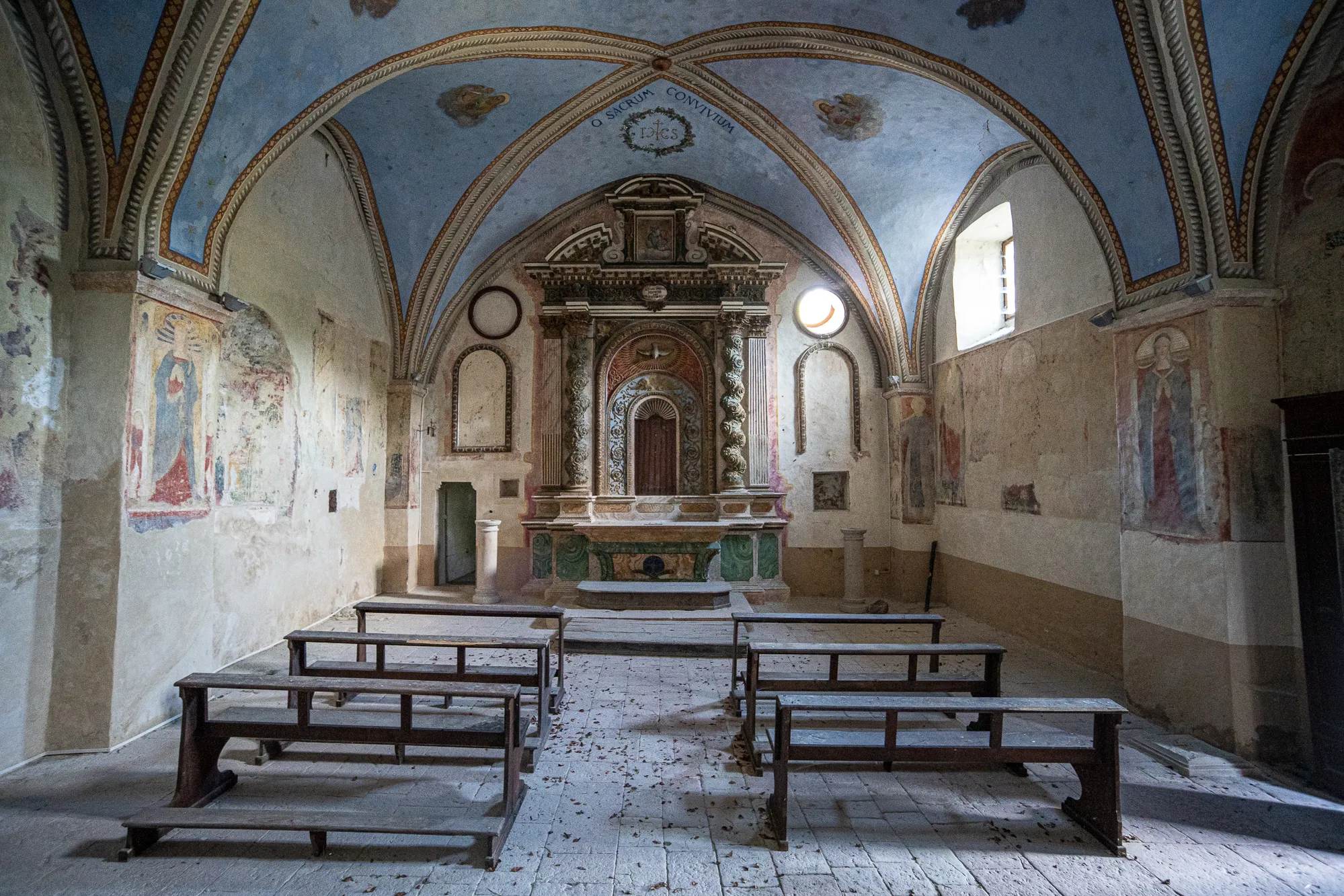 Innenraum einer alten Kirche mit Bänken, Altar und Wandmalereien