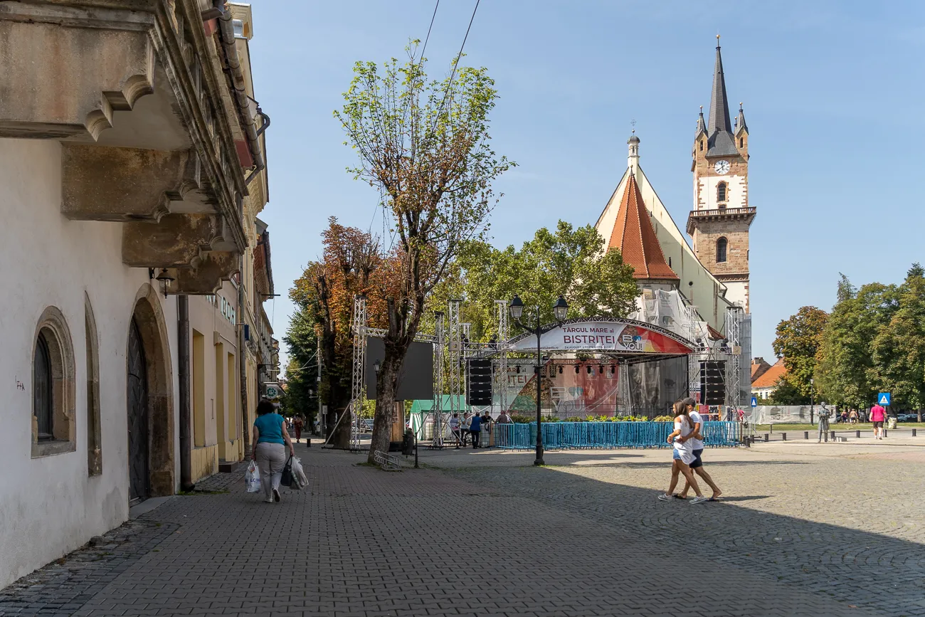 Kirche mit Turm und Bühne im Hintergrund, Menschen auf Kopfsteinpflaster