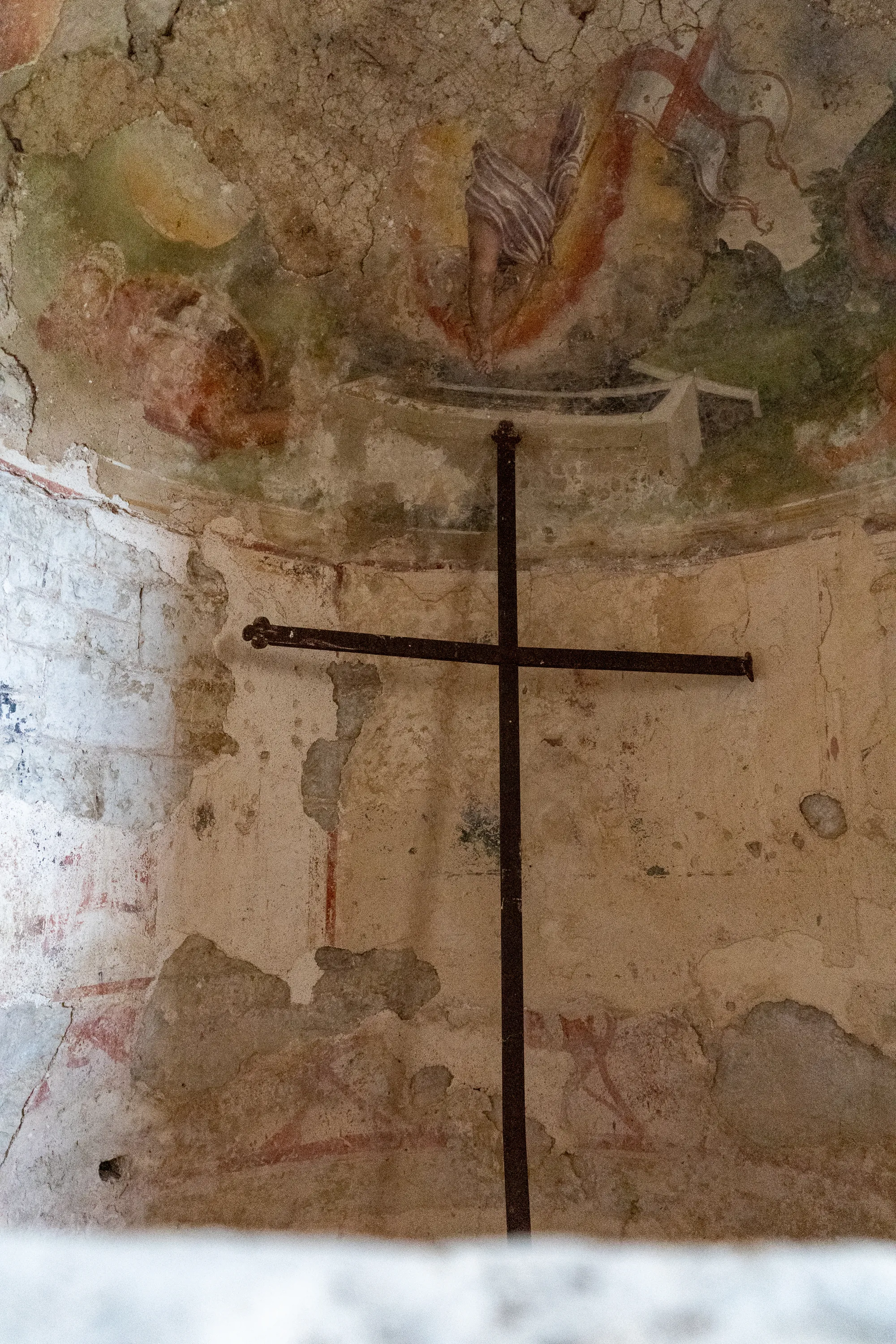 Alter Steinbau mit Kreuz und verblassten Wandmalereien