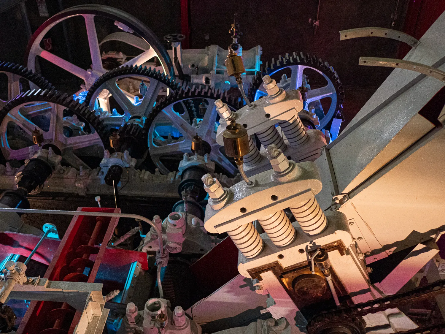 Industrielle Maschinen mit Zahnrädern und Kabeln in blau-weißem Licht