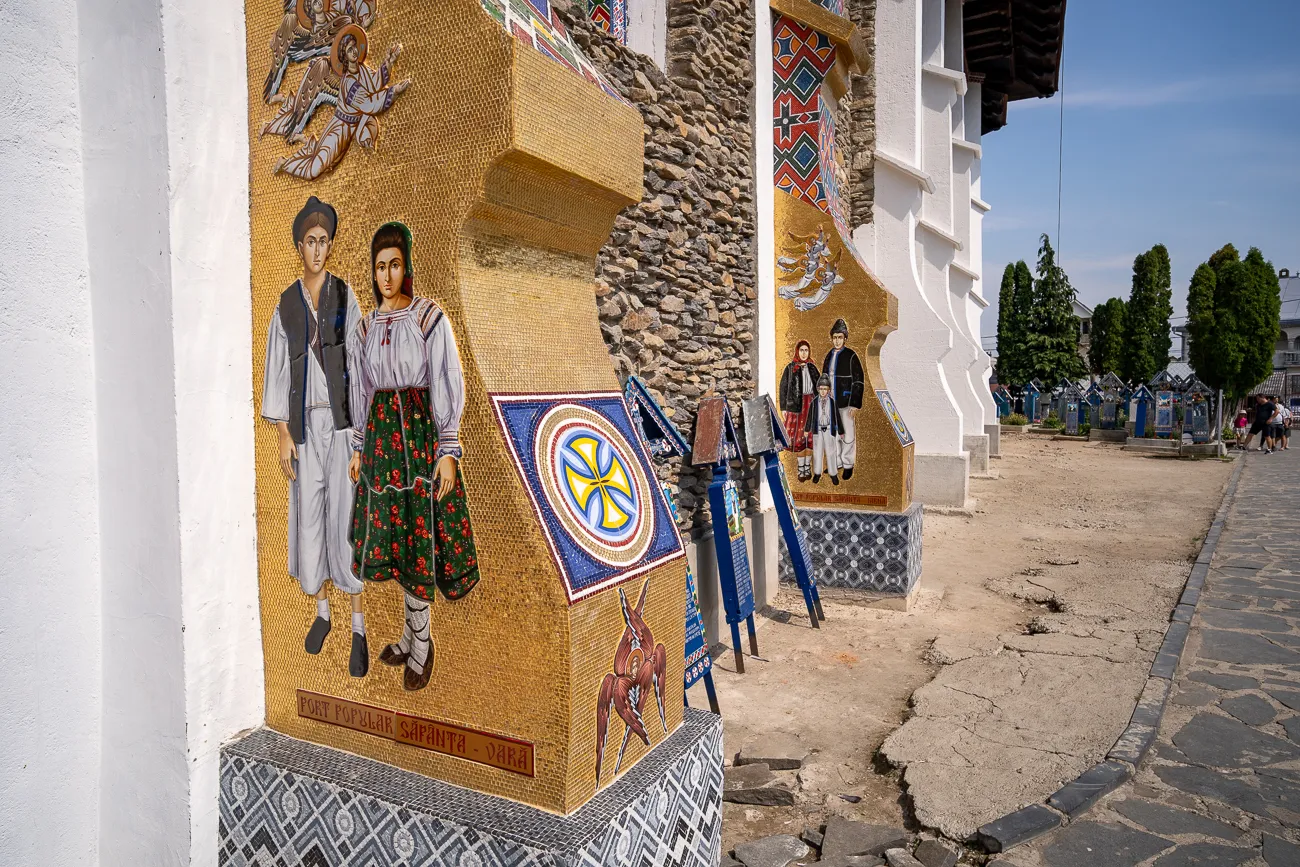 Mosaik mit traditionellen Figuren an einer Kirchenwand, gepflasterte Straße im Hintergrund