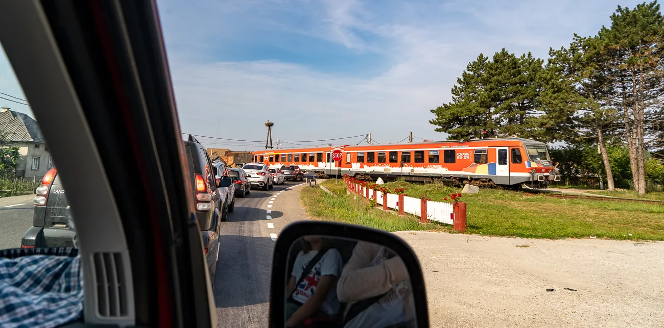 orange zug fährt an straße vorbei, spiegel reflektiert autoinnenraum