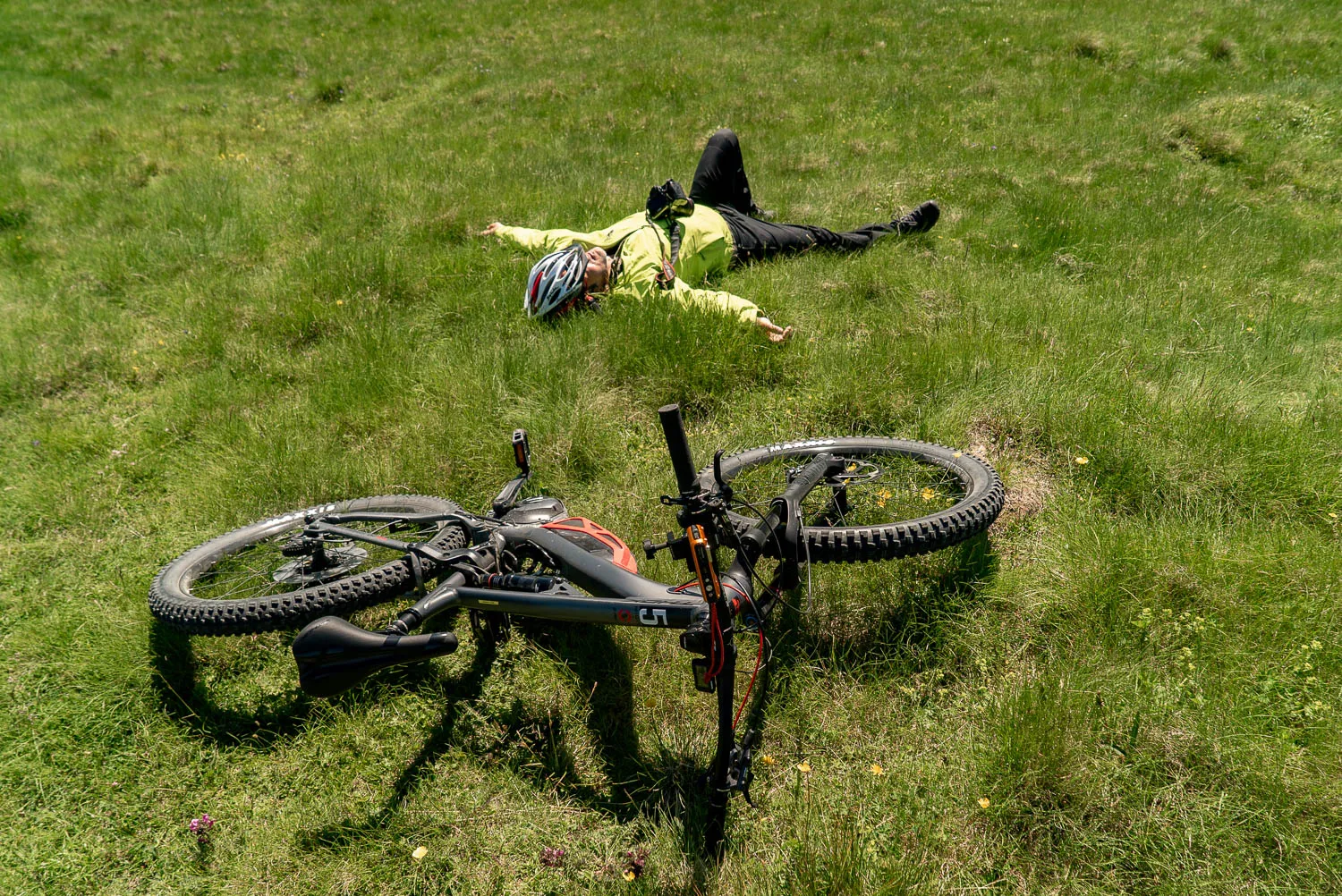 Mann liegt auf grünem Gras, Mountainbike daneben