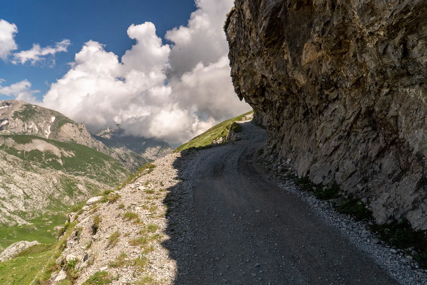 Gesteiniger Pfad an steiler Bergwand unter wolkenverhangenem Himmel