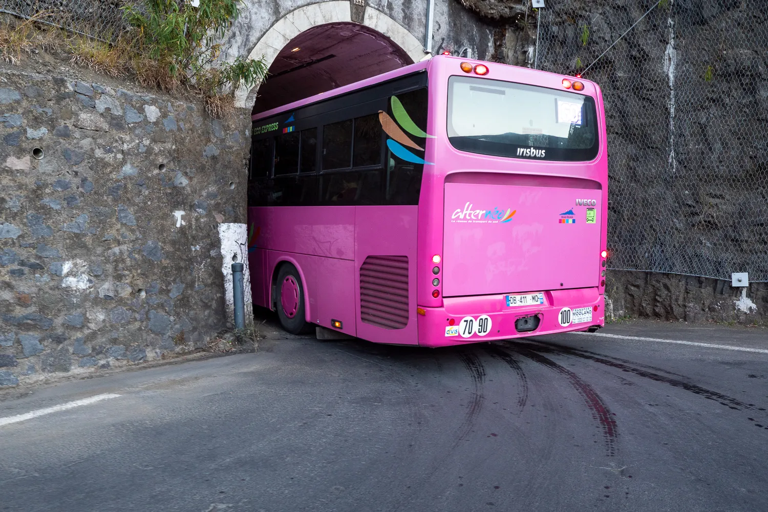 Pink bus fährt durch Steinbogen unter Straße
