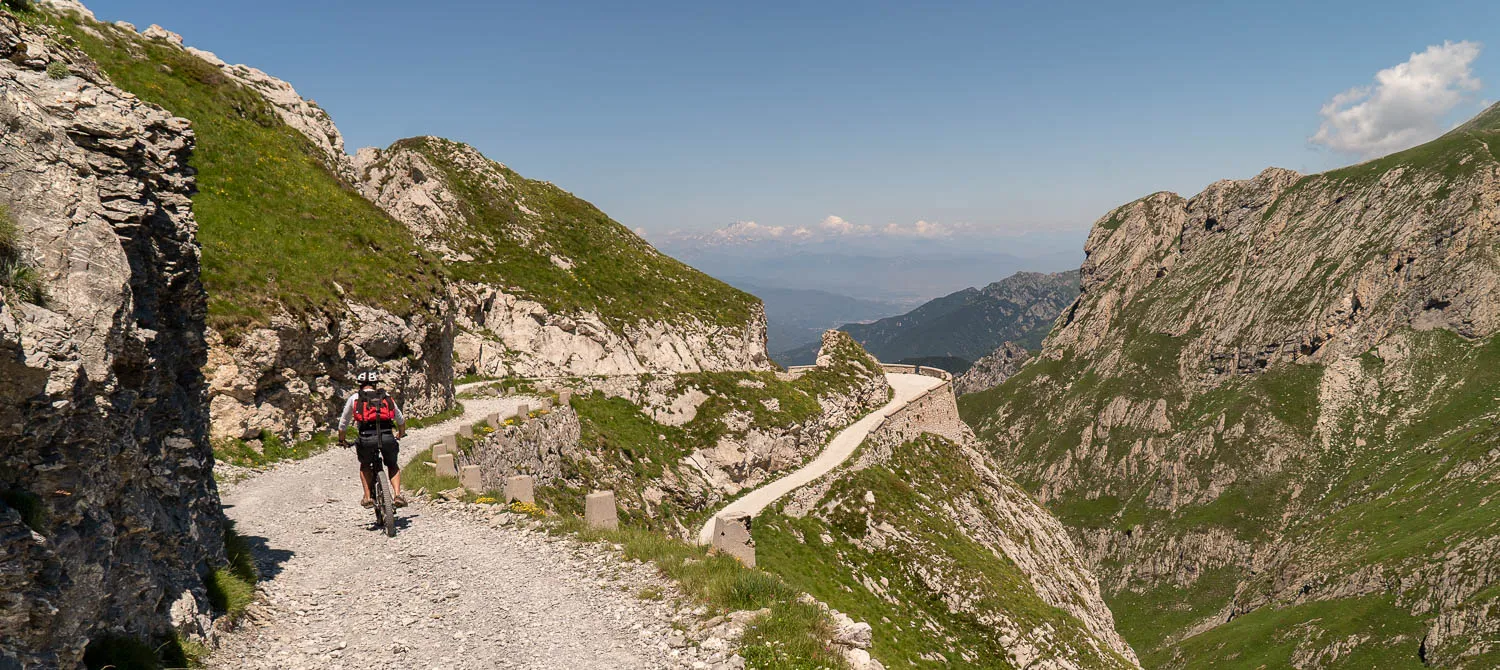 Radfahrer auf steinigem Bergpfad mit Blick auf Tal und Berge