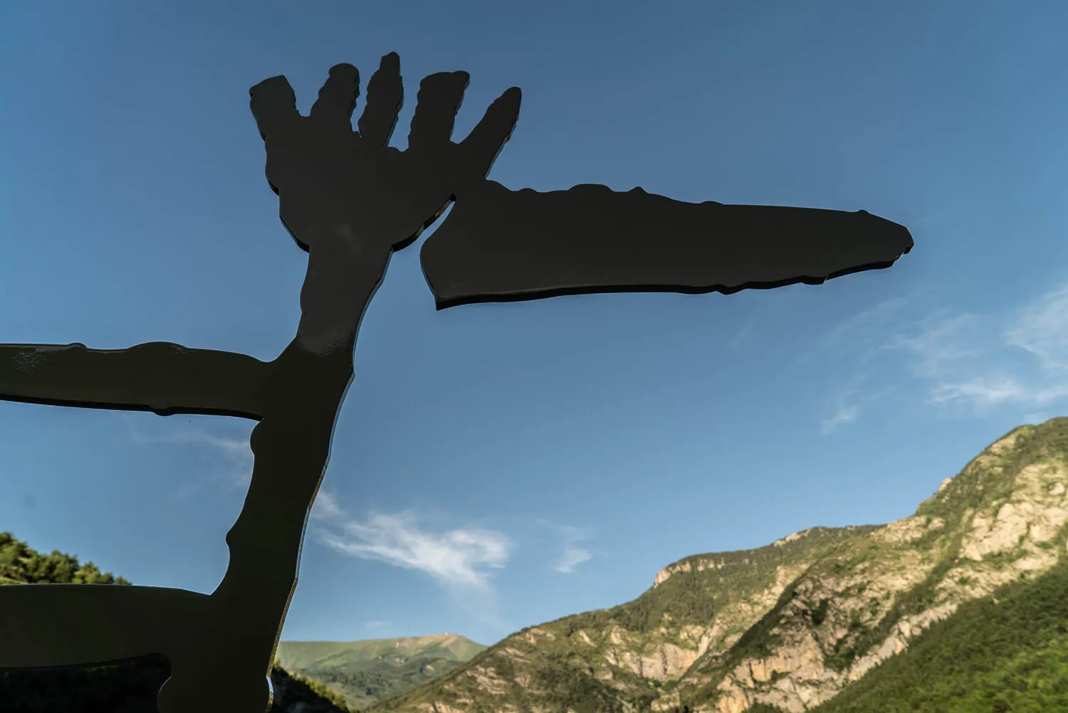 Schattenbild einer Skulptur vor blauem Himmel und Bergen