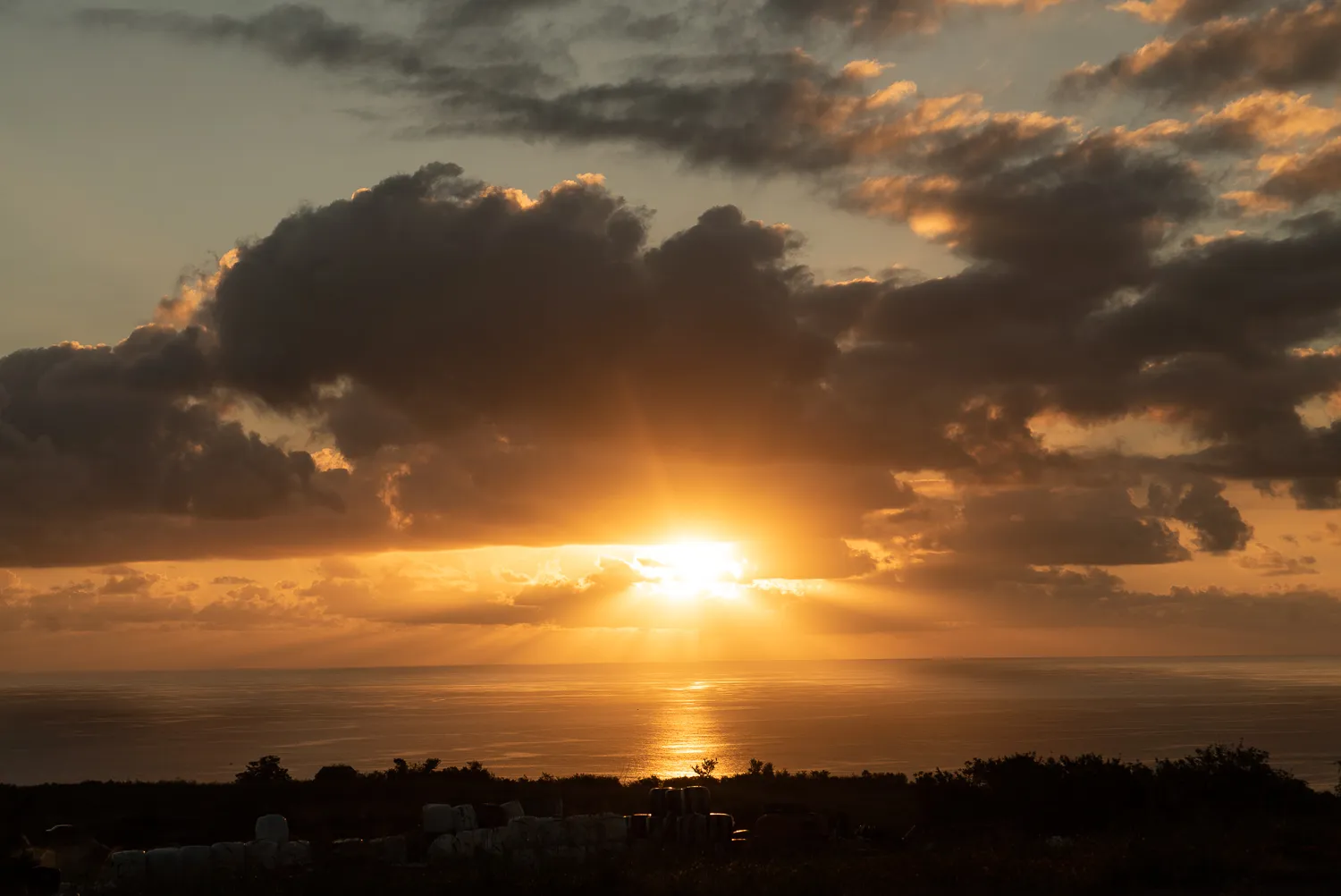 Sonnenuntergang über dem Meer mit dramatischen Wolken und Lichtstrahlen.