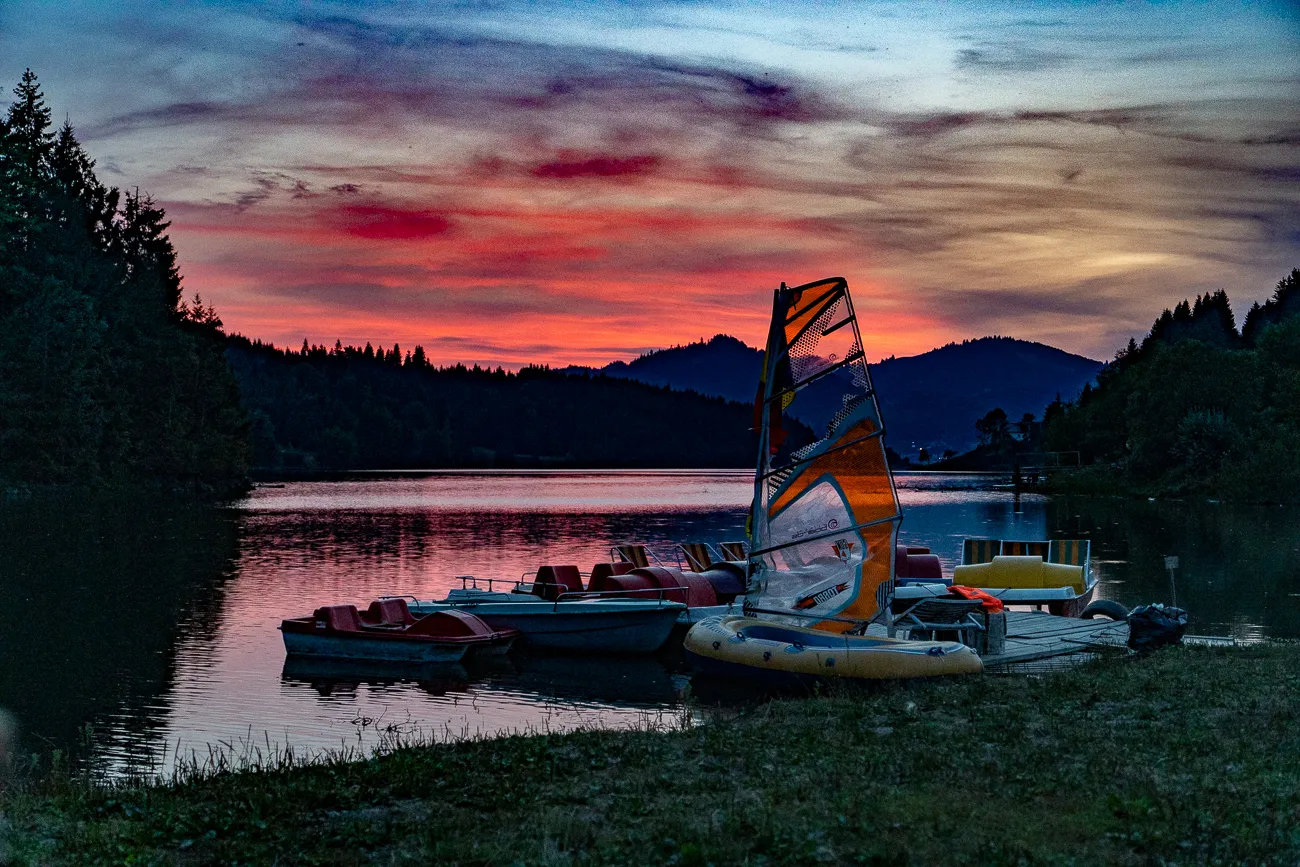 Sonnenuntergang über See mit Segelboot und Paddelbooten