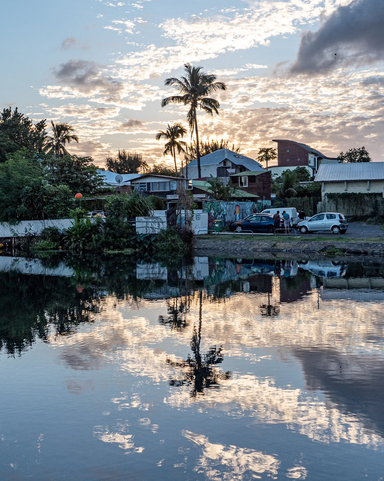 Spiegelung von Häusern und Palmen im Wasser bei Sonnenuntergang