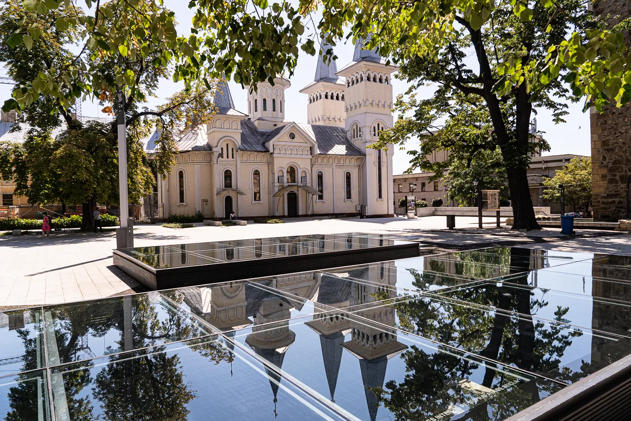 Spiegelung einer Kirche in einem Wasserbecken unter Bäumen