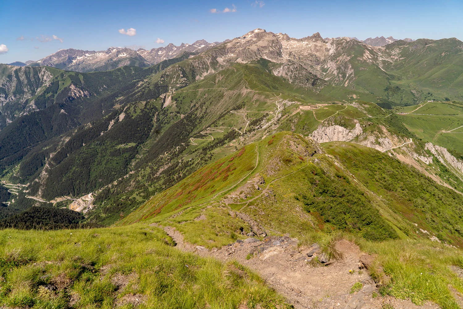grüne berglandschaft mit steigender wanderspur unter blauem himmel
