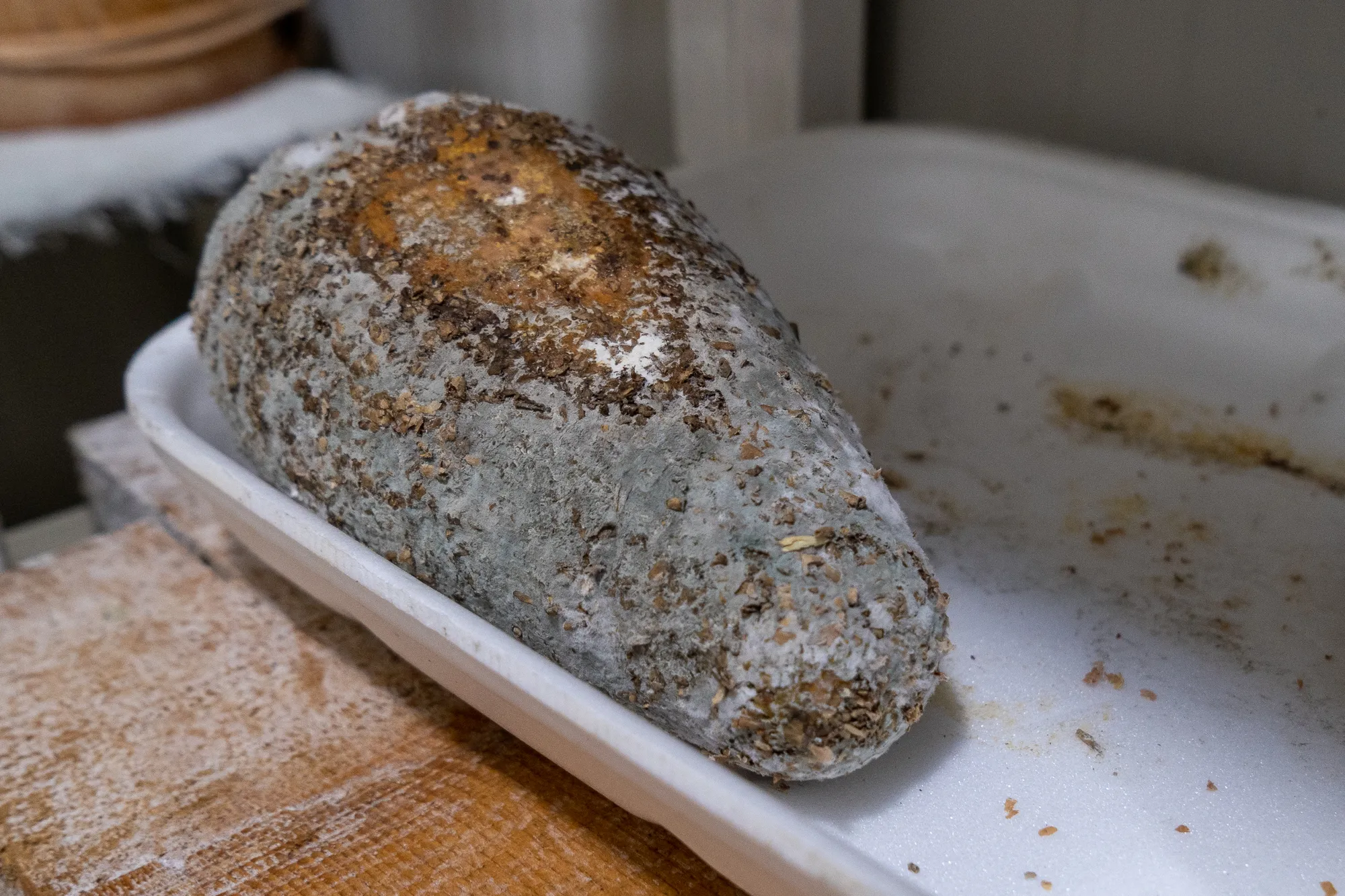 Grauer Stein mit braunen Flecken liegt in weißem Teller auf Holzplatte.