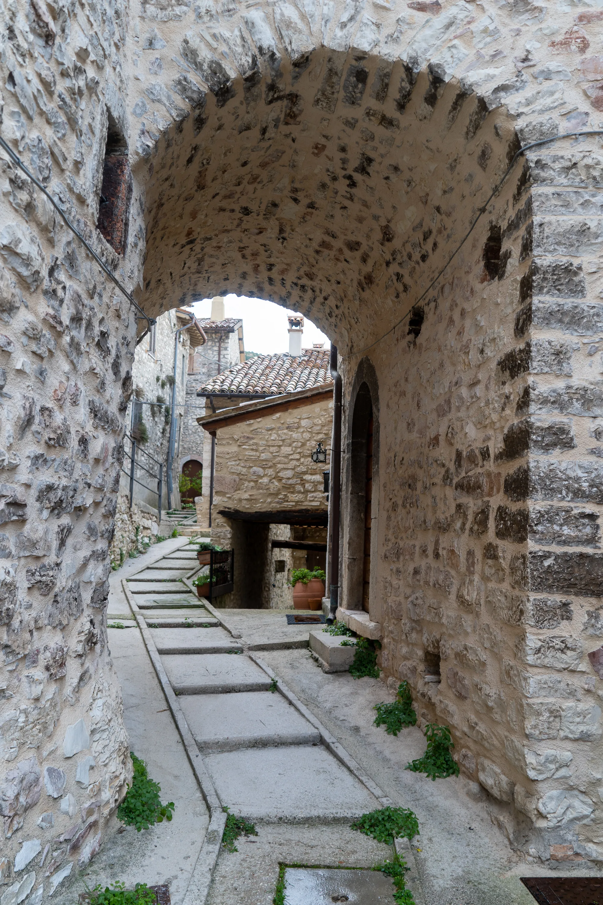 Steinbogen über steinerner Gasse in mittelalterlichem Dorf