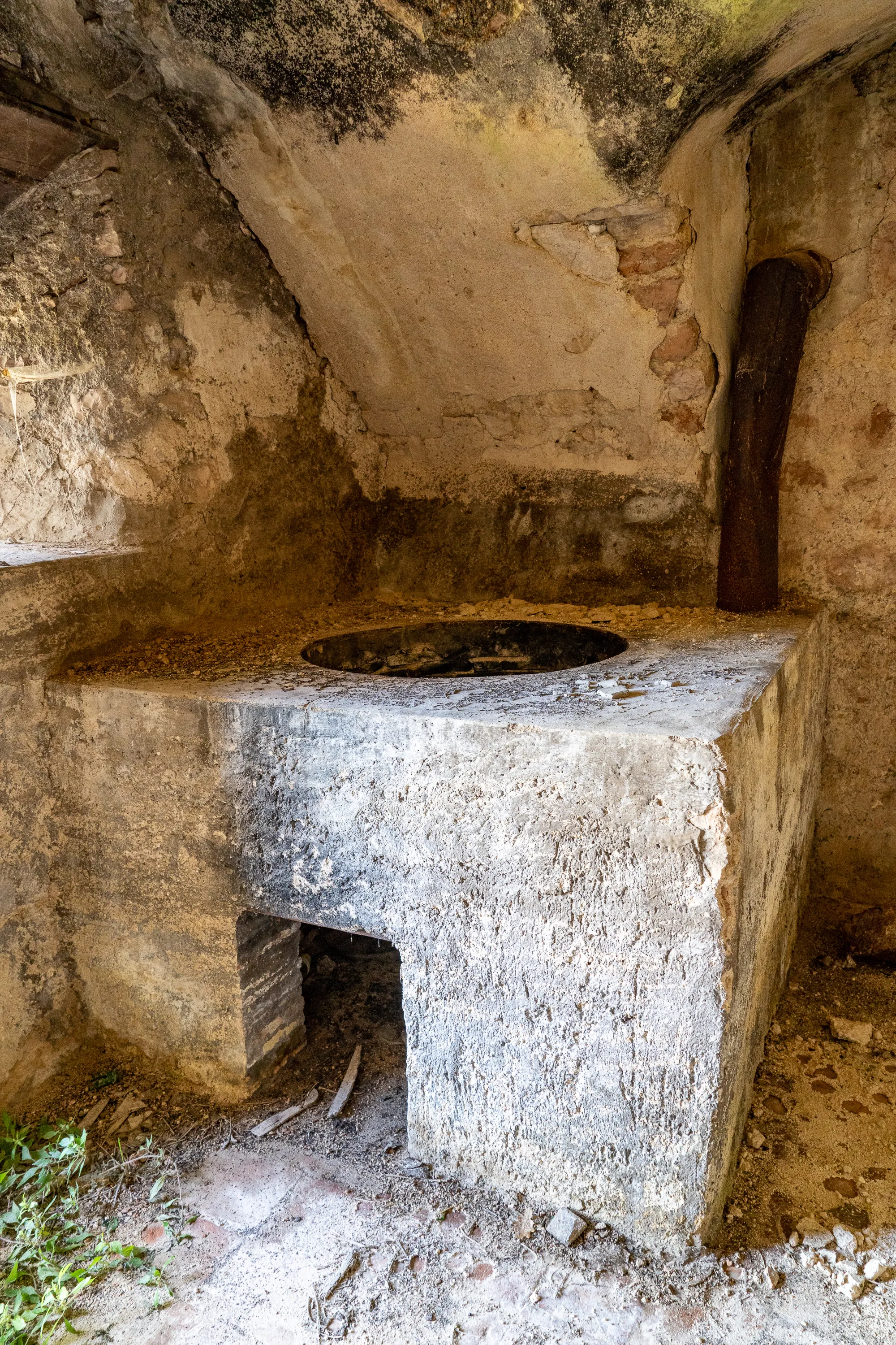 Alter Steinofen in rustikalem Holzhaus mit rauchförmigem Schornstein
